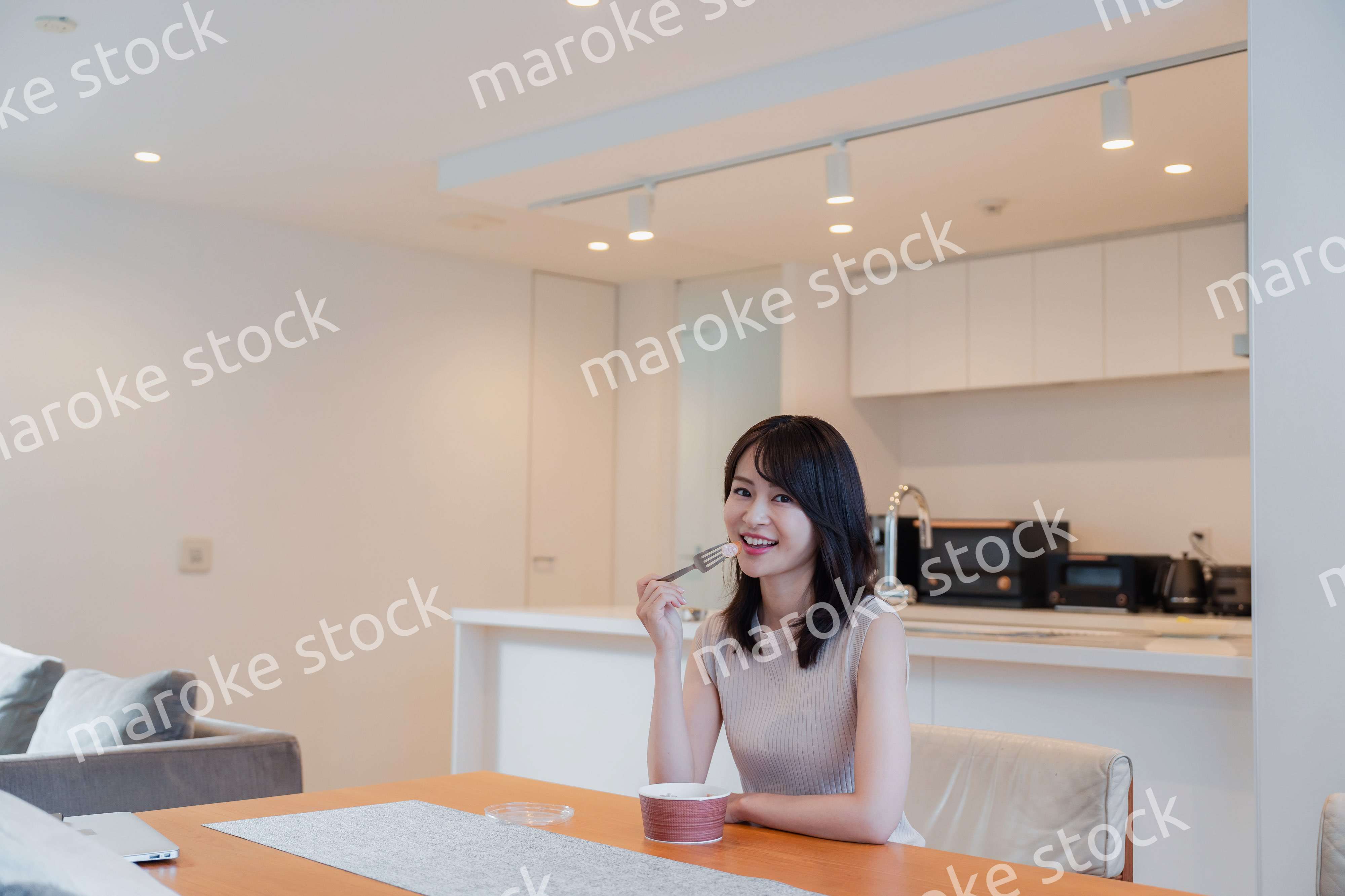 家でコンビニ弁当を食べる若い女性