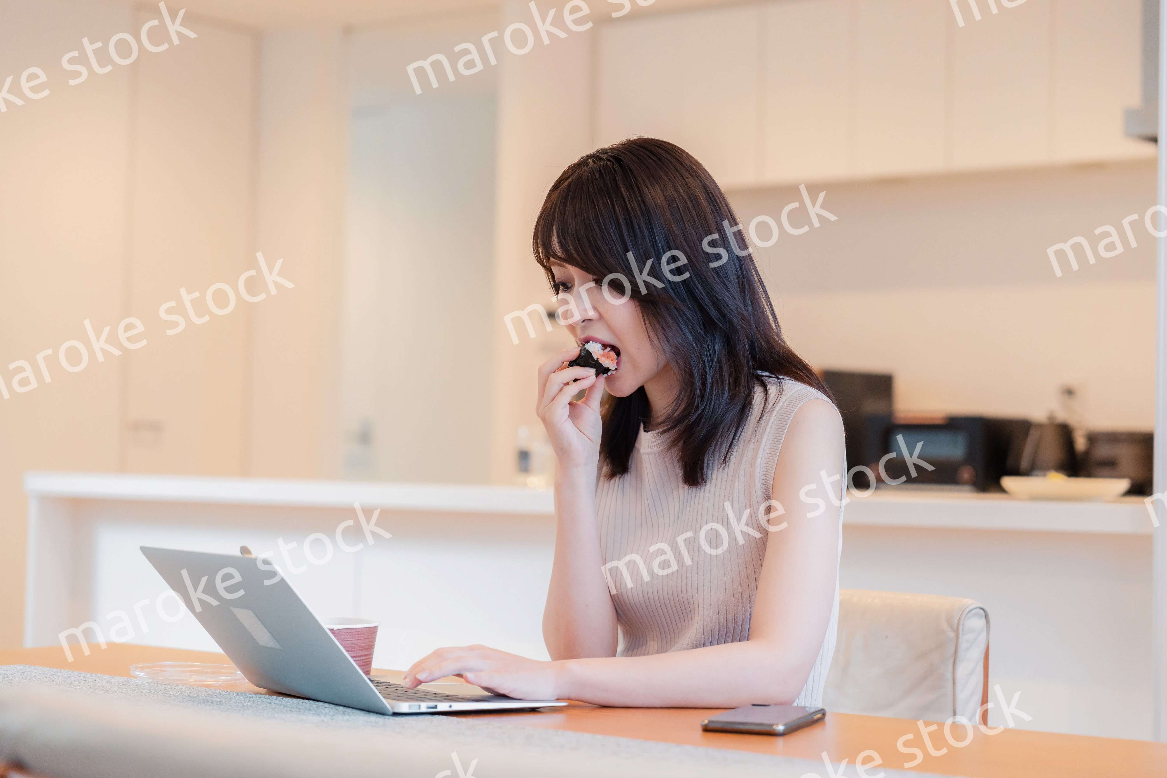 テレワークをしながらごはんを食べる多忙な女性