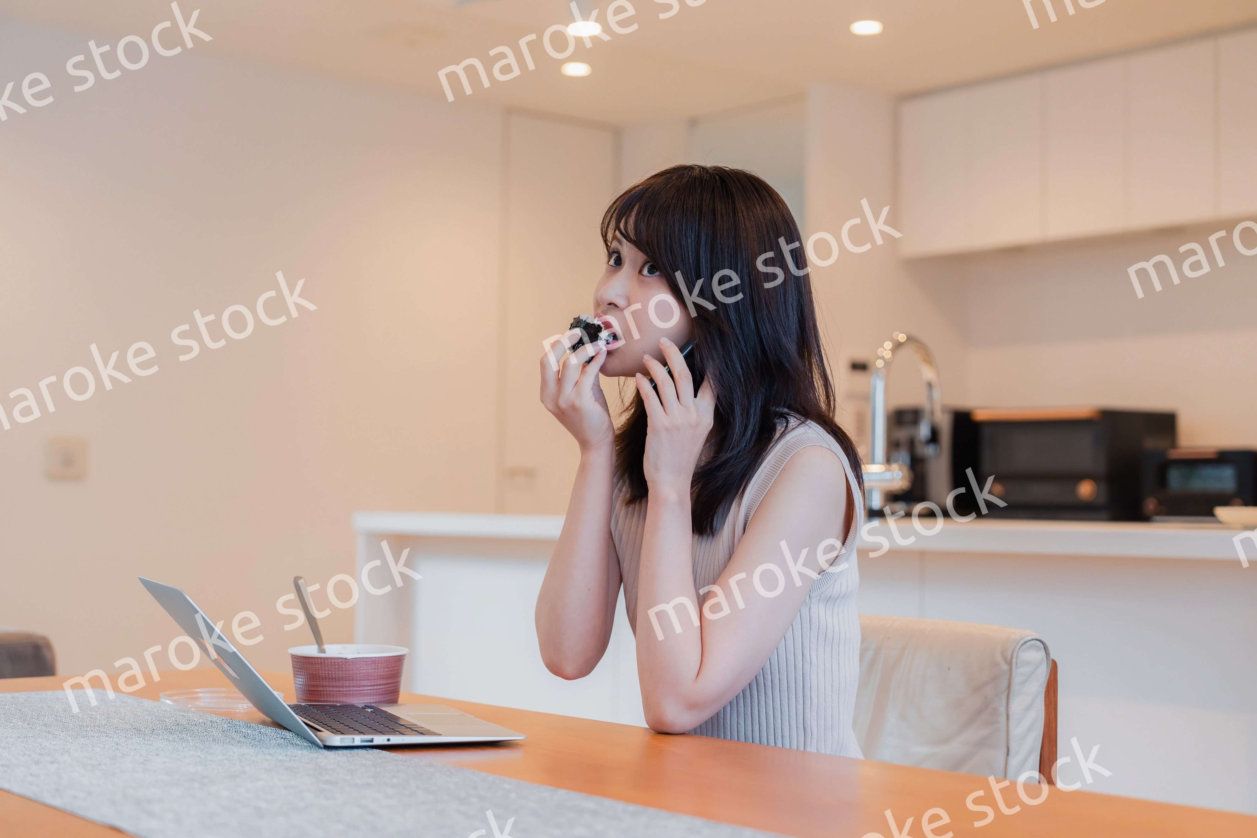 テレワークをしながらごはんを食べる多忙な女性