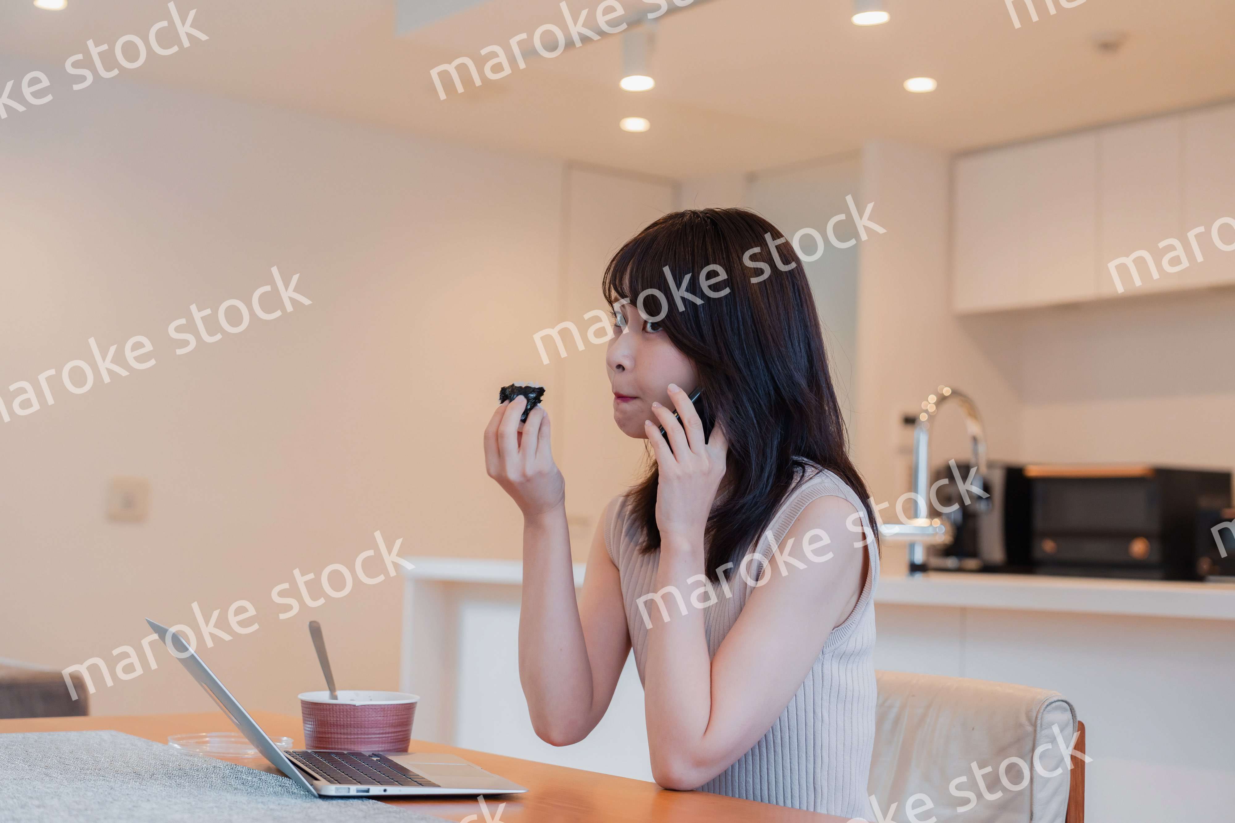 テレワークをしながらごはんを食べる多忙な女性