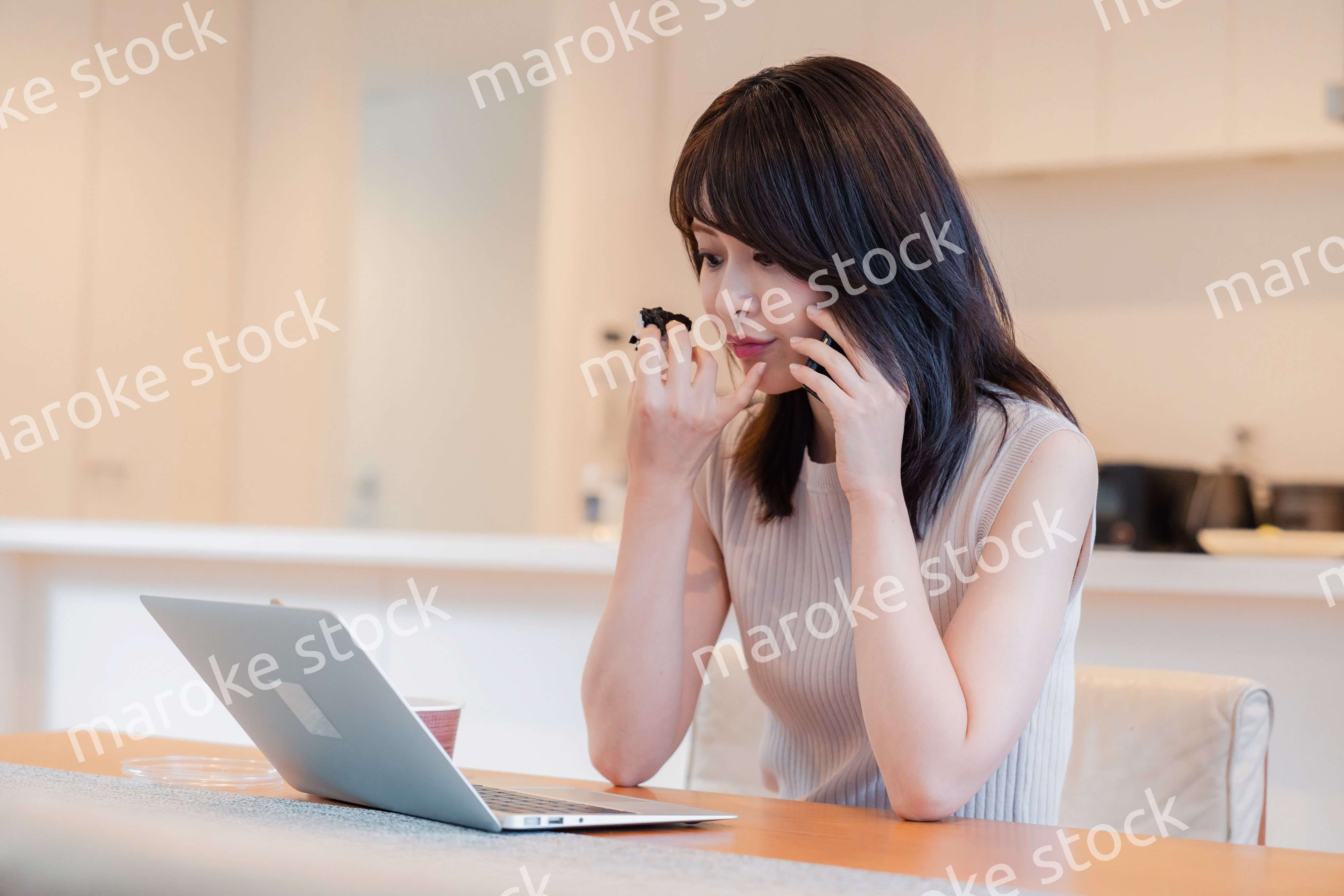 テレワークをしながらごはんを食べる多忙な女性