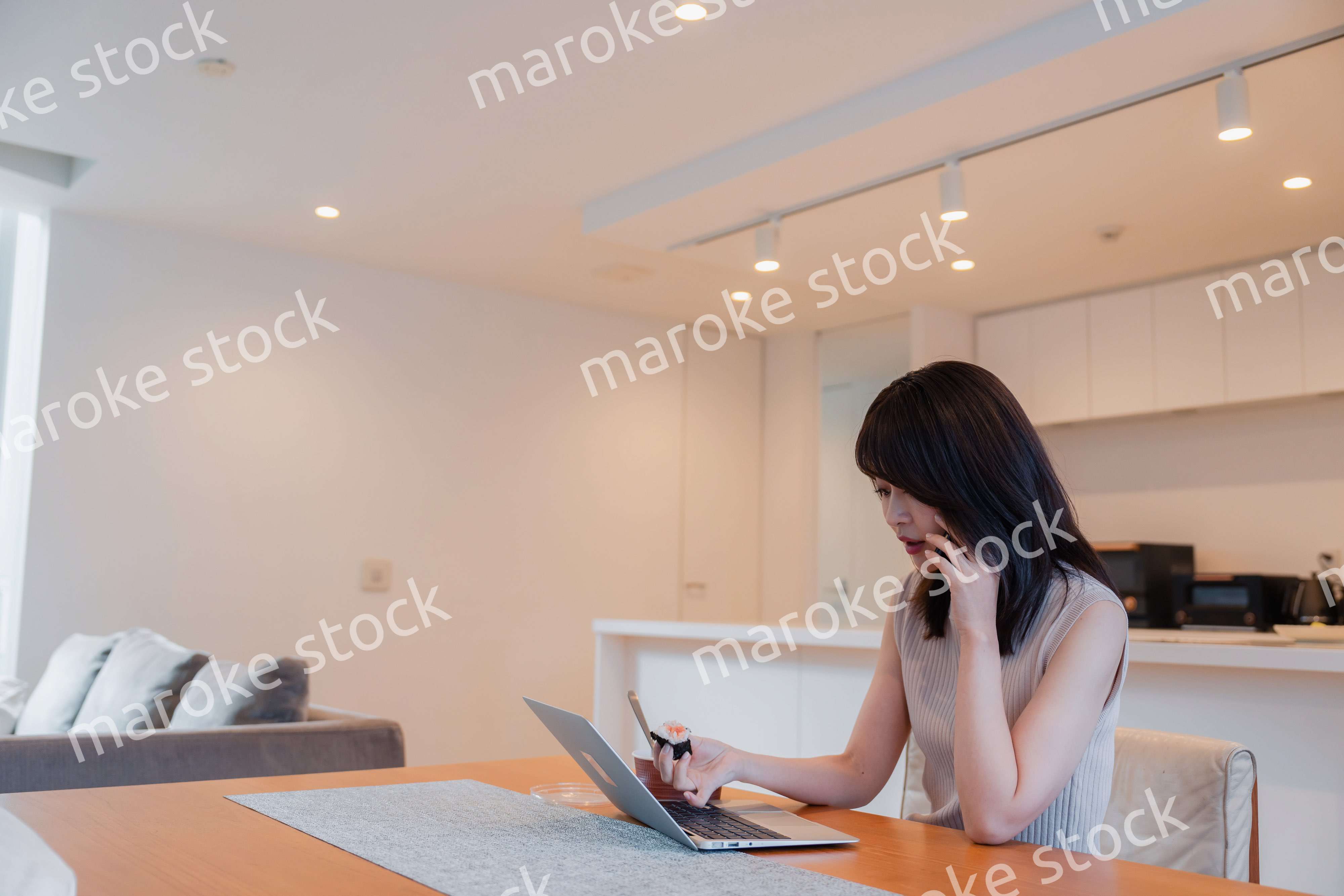 テレワークをしながらごはんを食べる多忙な女性