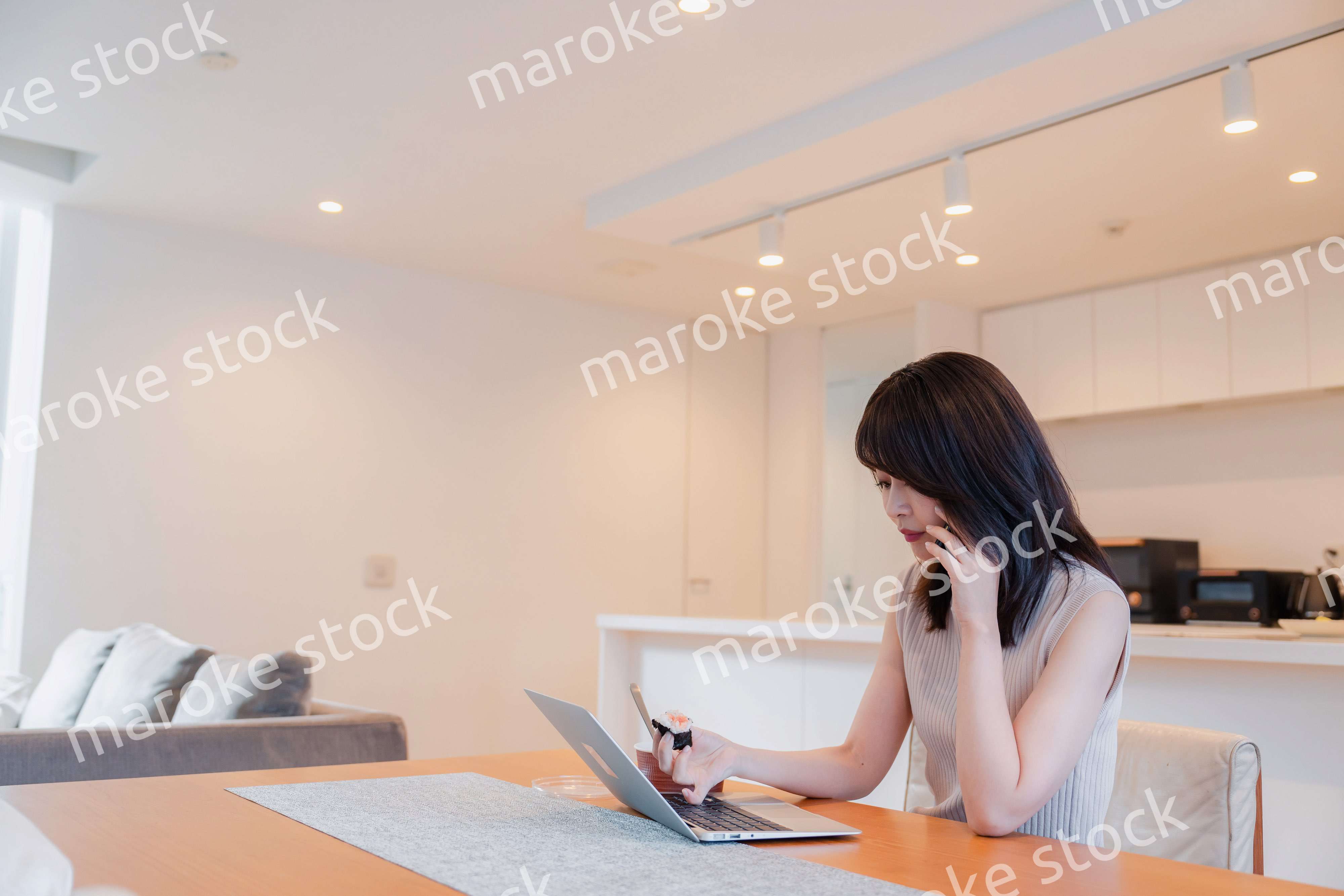 テレワークをしながらごはんを食べる多忙な女性