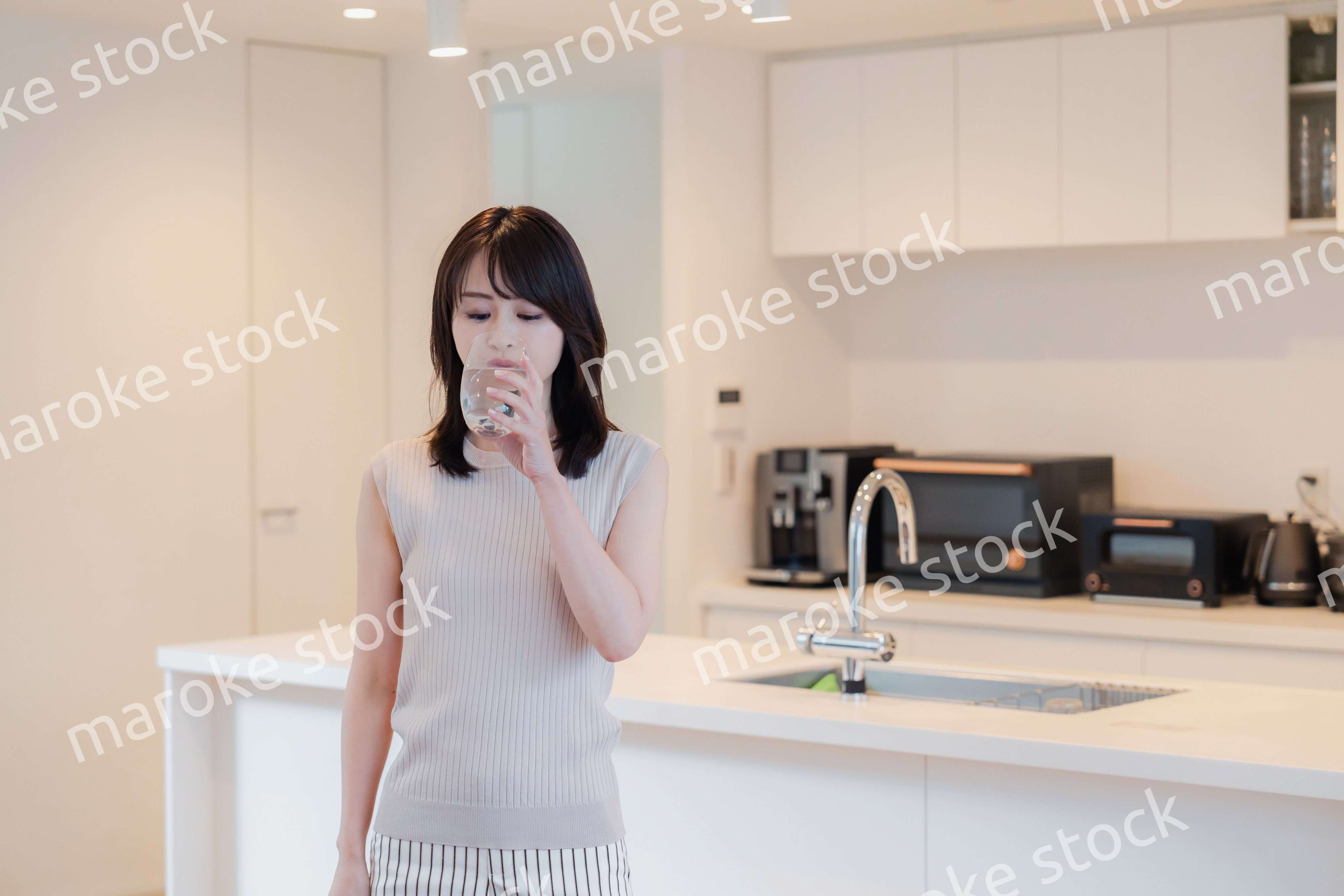 家で水を飲む若い女性