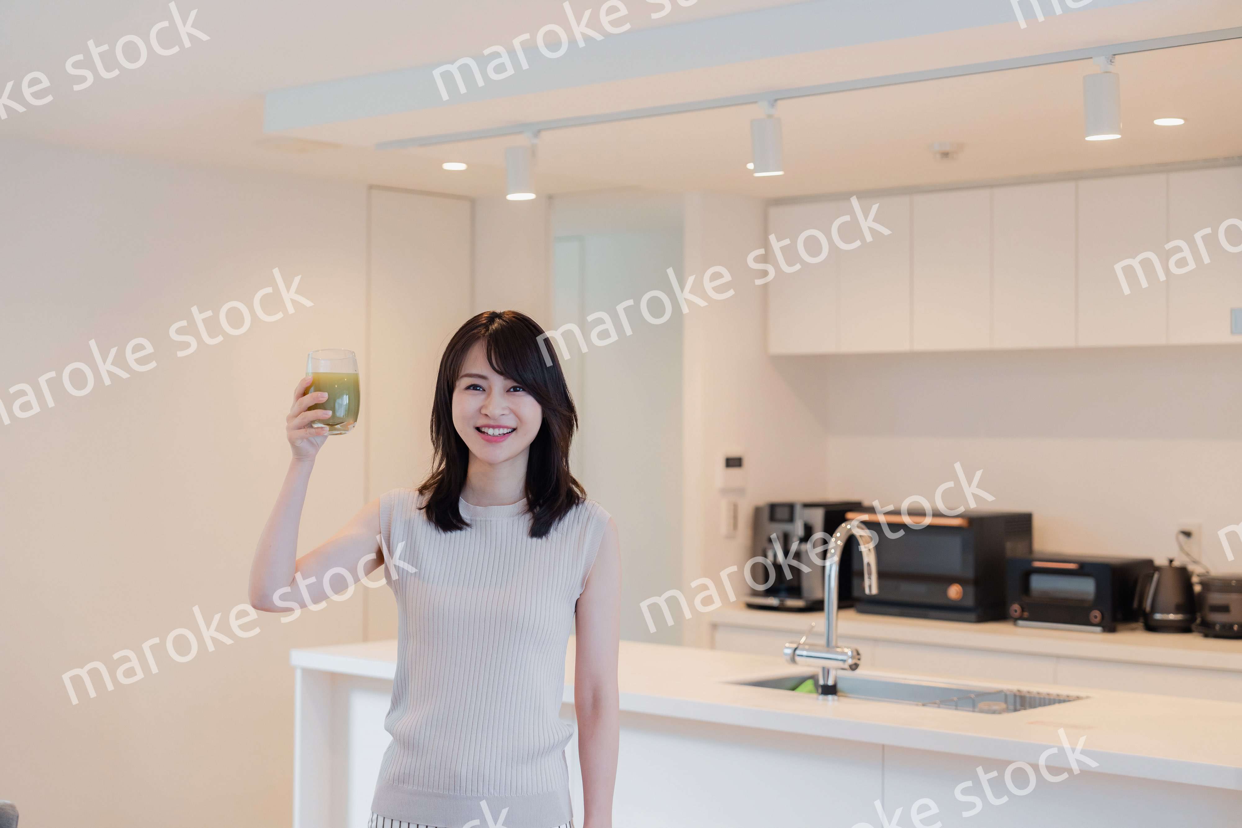 家でスムージーを飲む若い女性