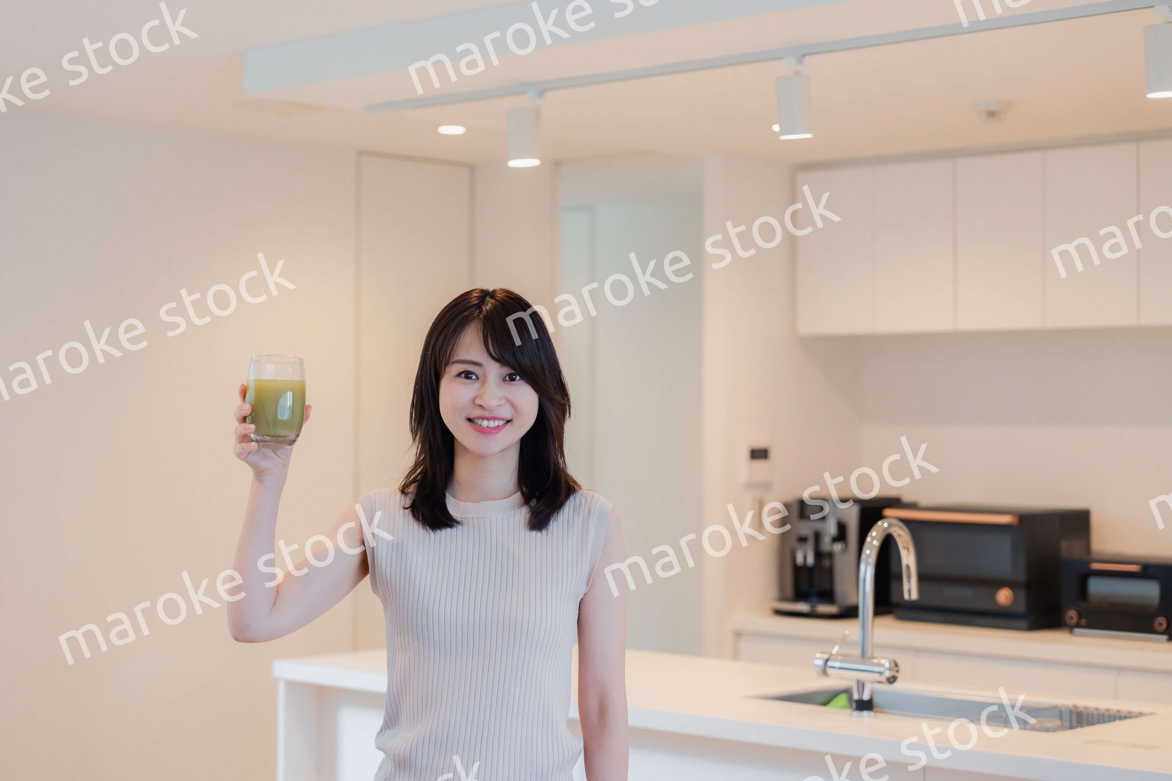 家でスムージーを飲む若い女性