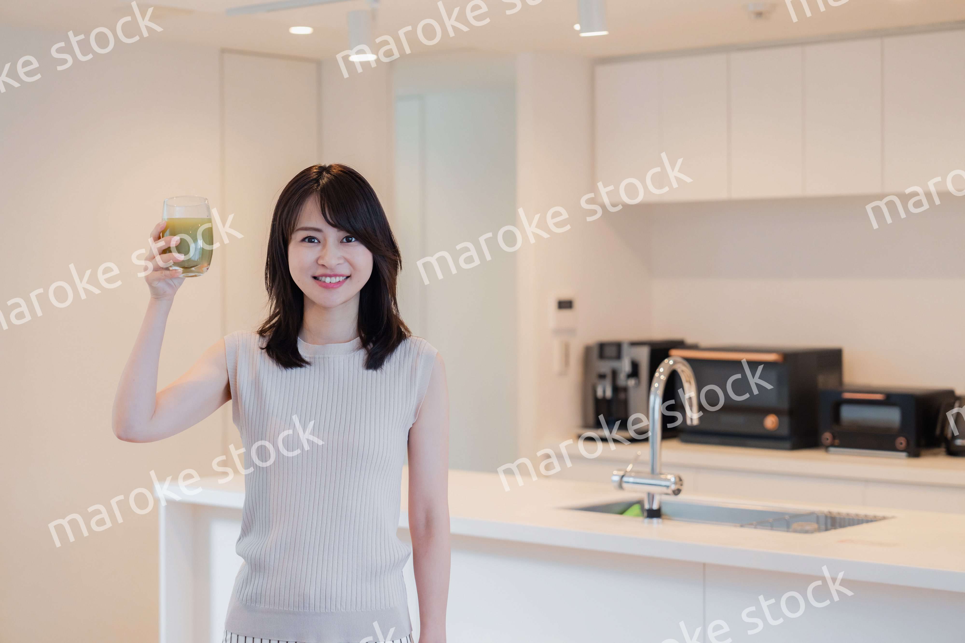 家でスムージーを飲む若い女性