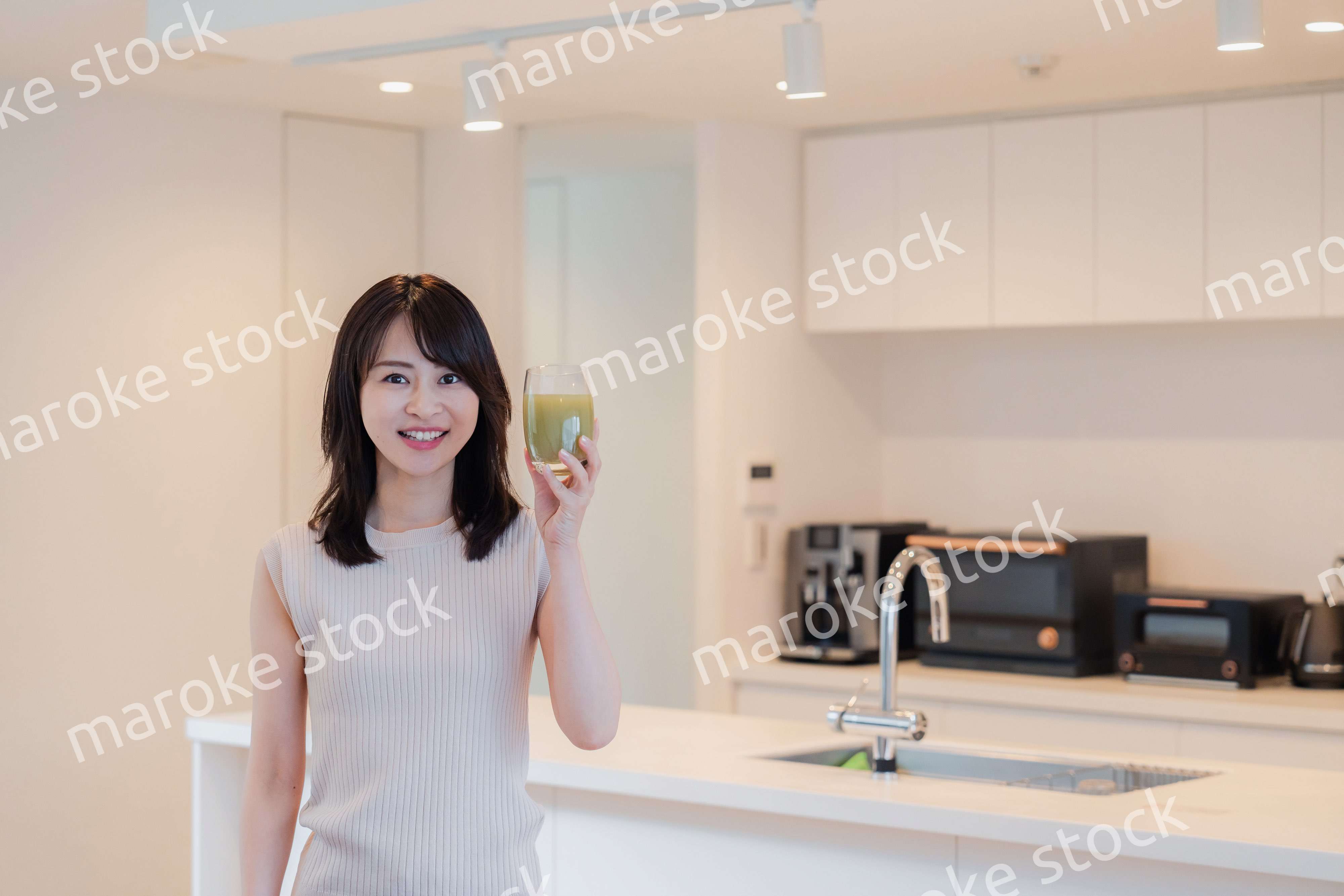 家でスムージーを飲む若い女性