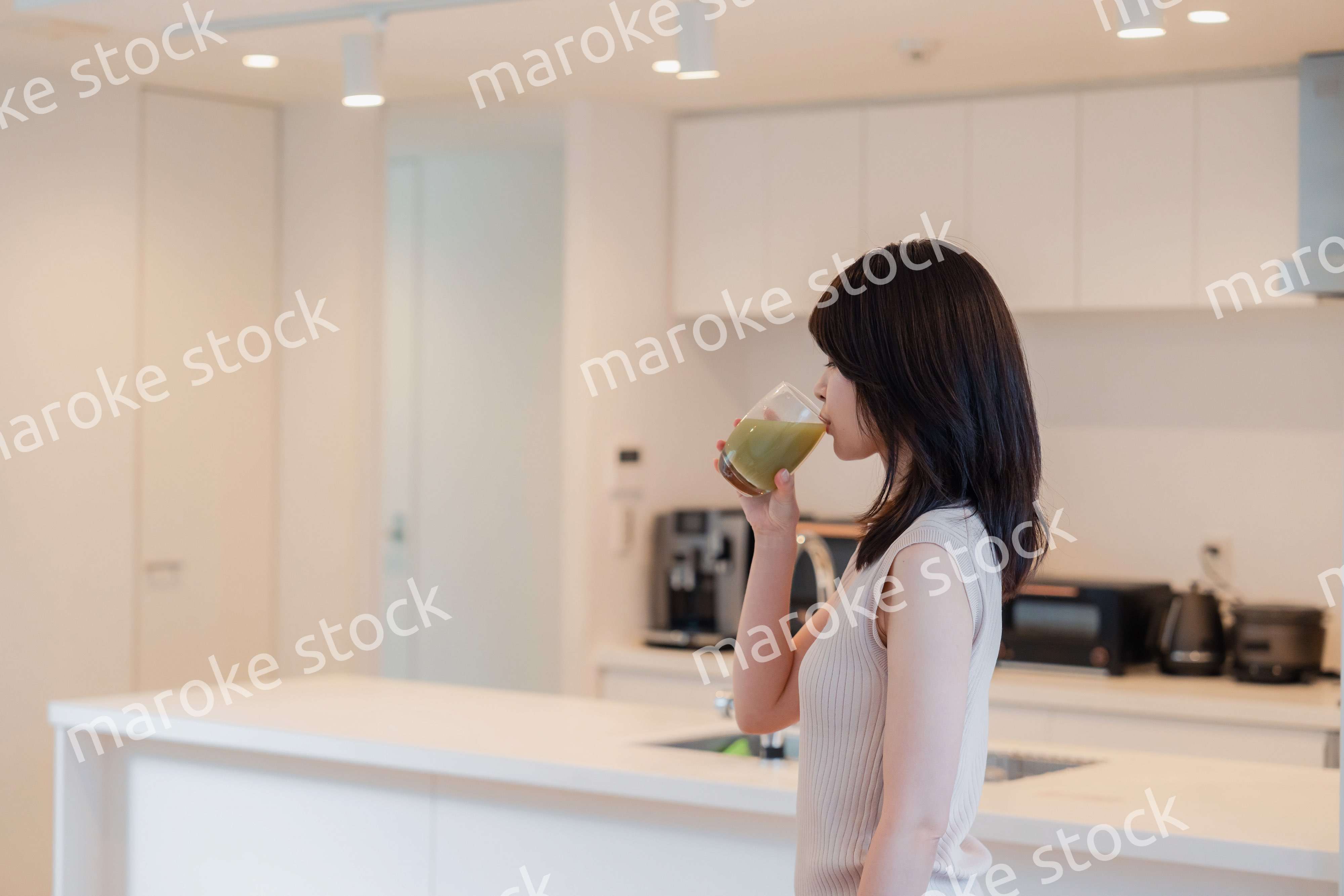 家でスムージーを飲む若い女性