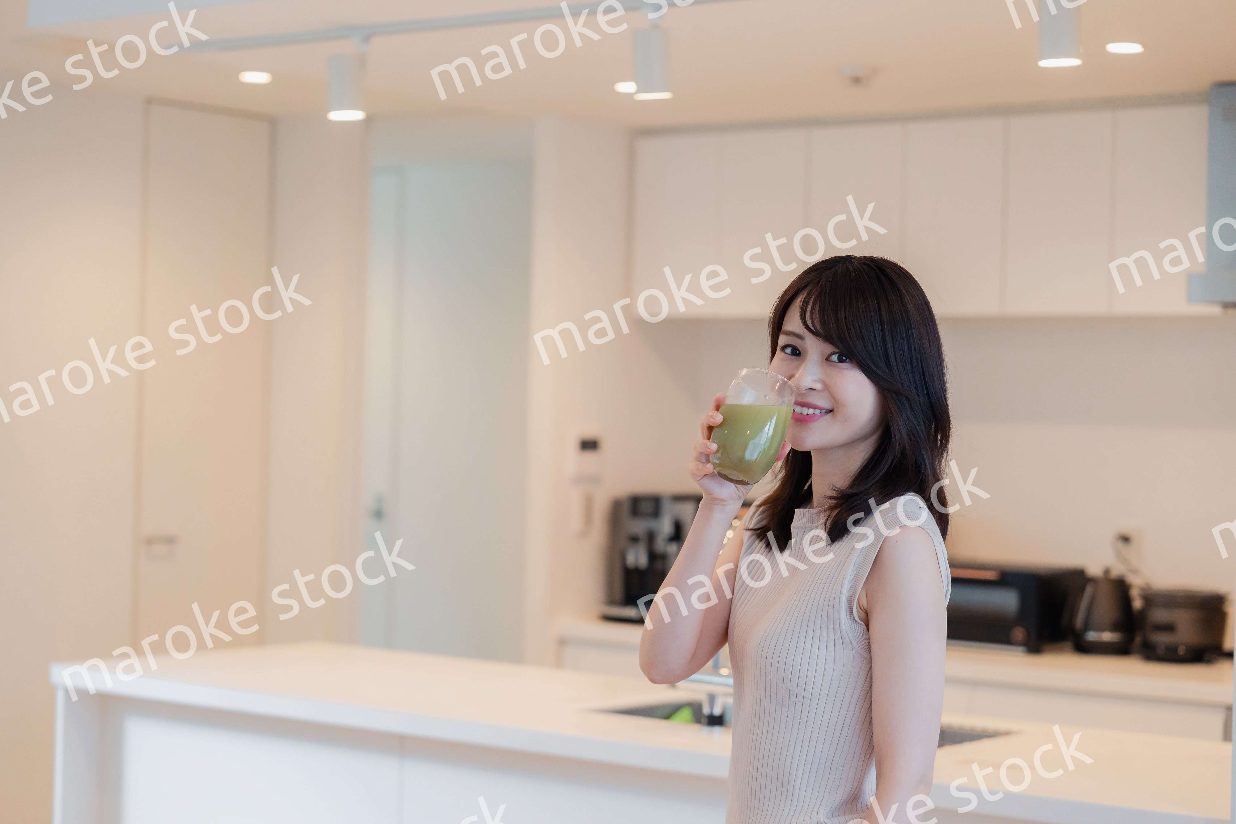 家でスムージーを飲む若い女性