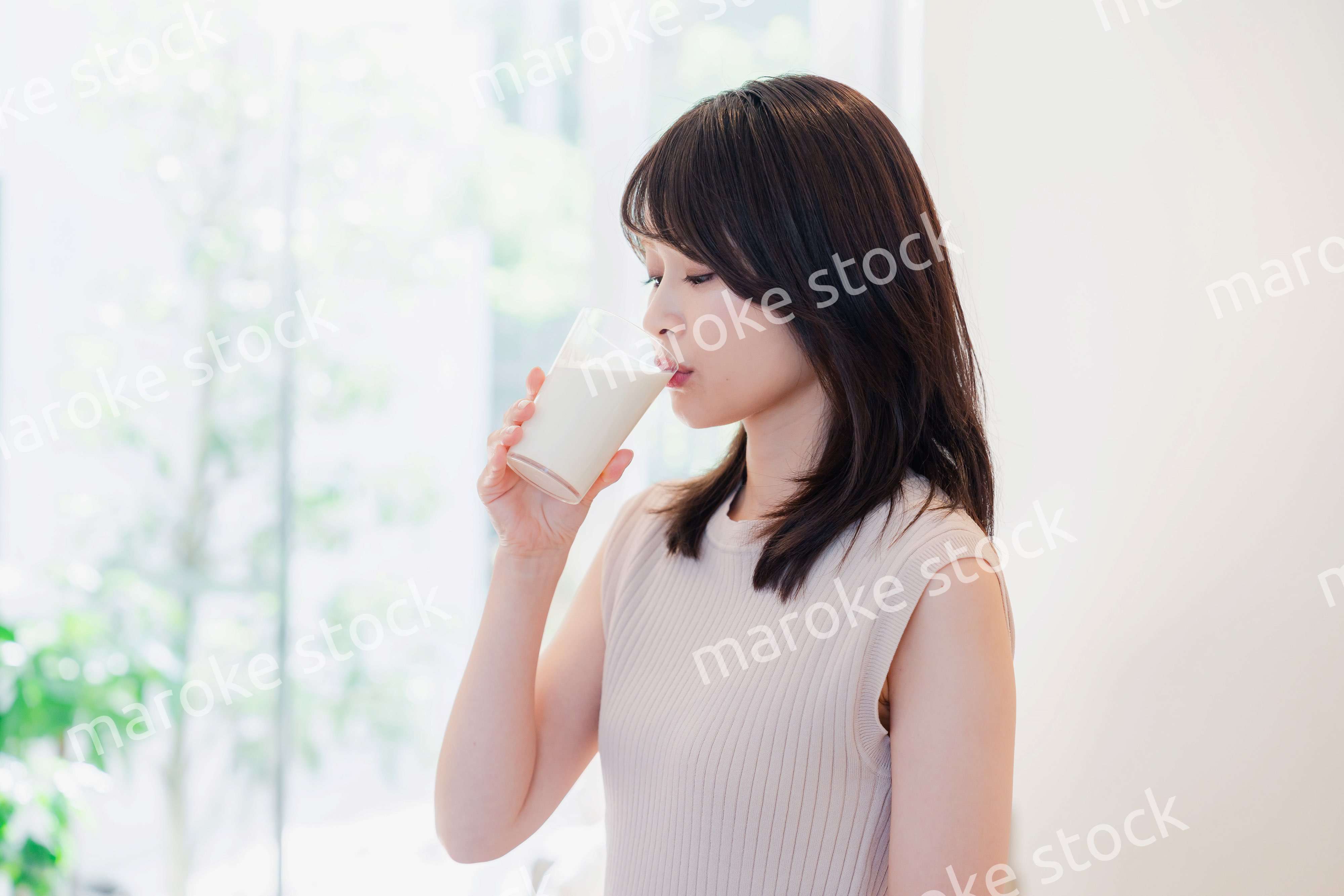 家でミルクを飲む若い女性