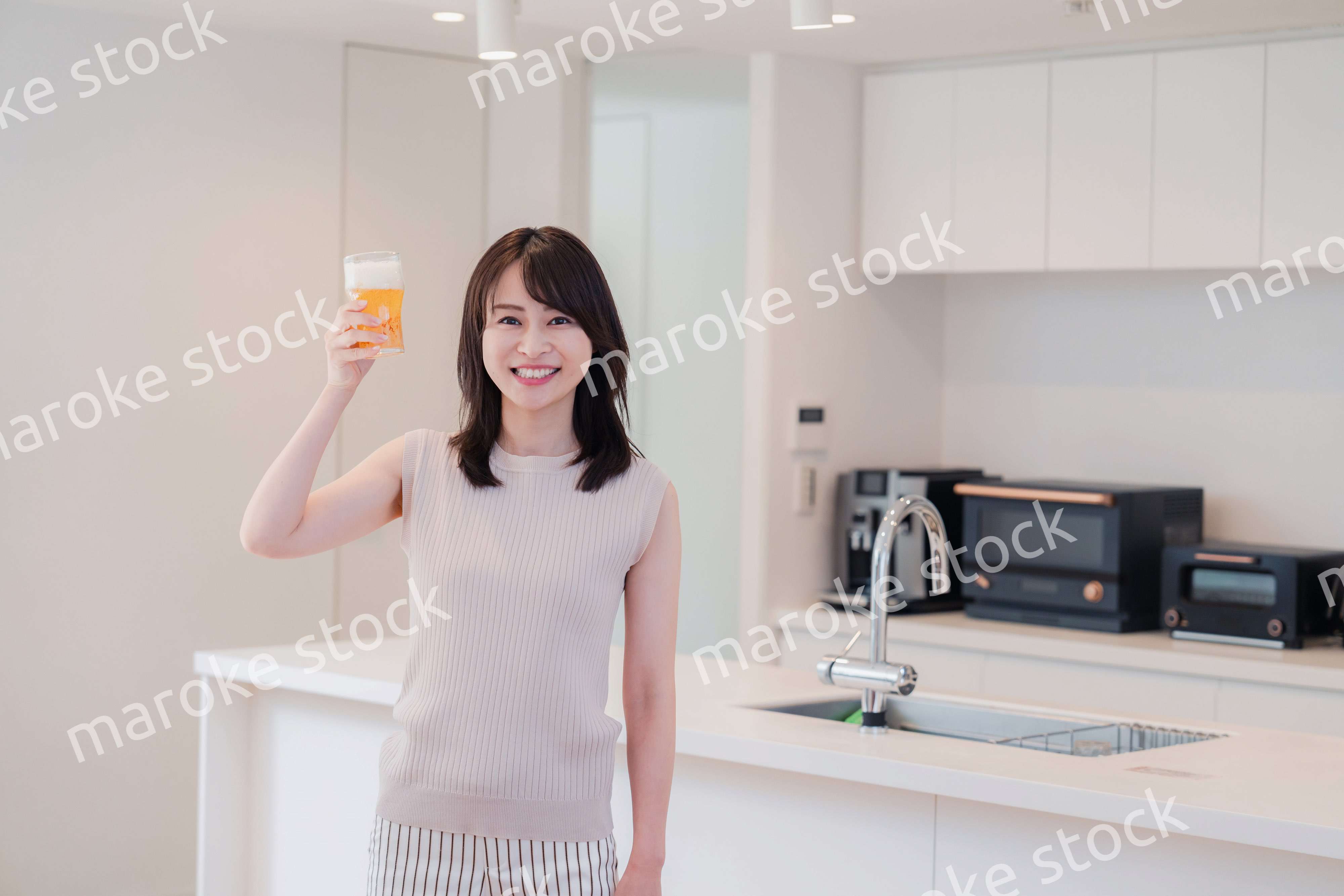 家事をしながらアルコールを飲む若い女性