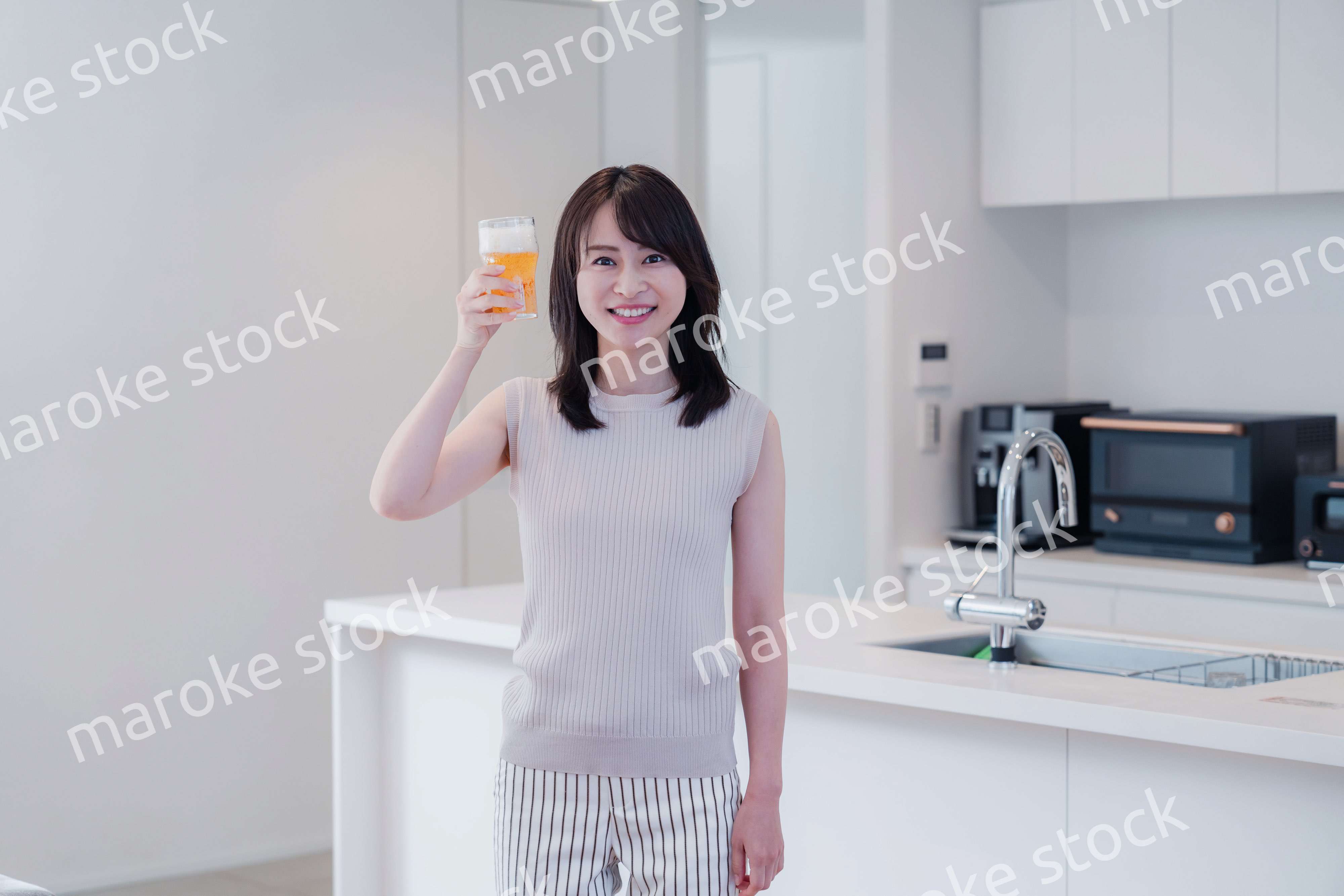 家事をしながらアルコールを飲む若い女性