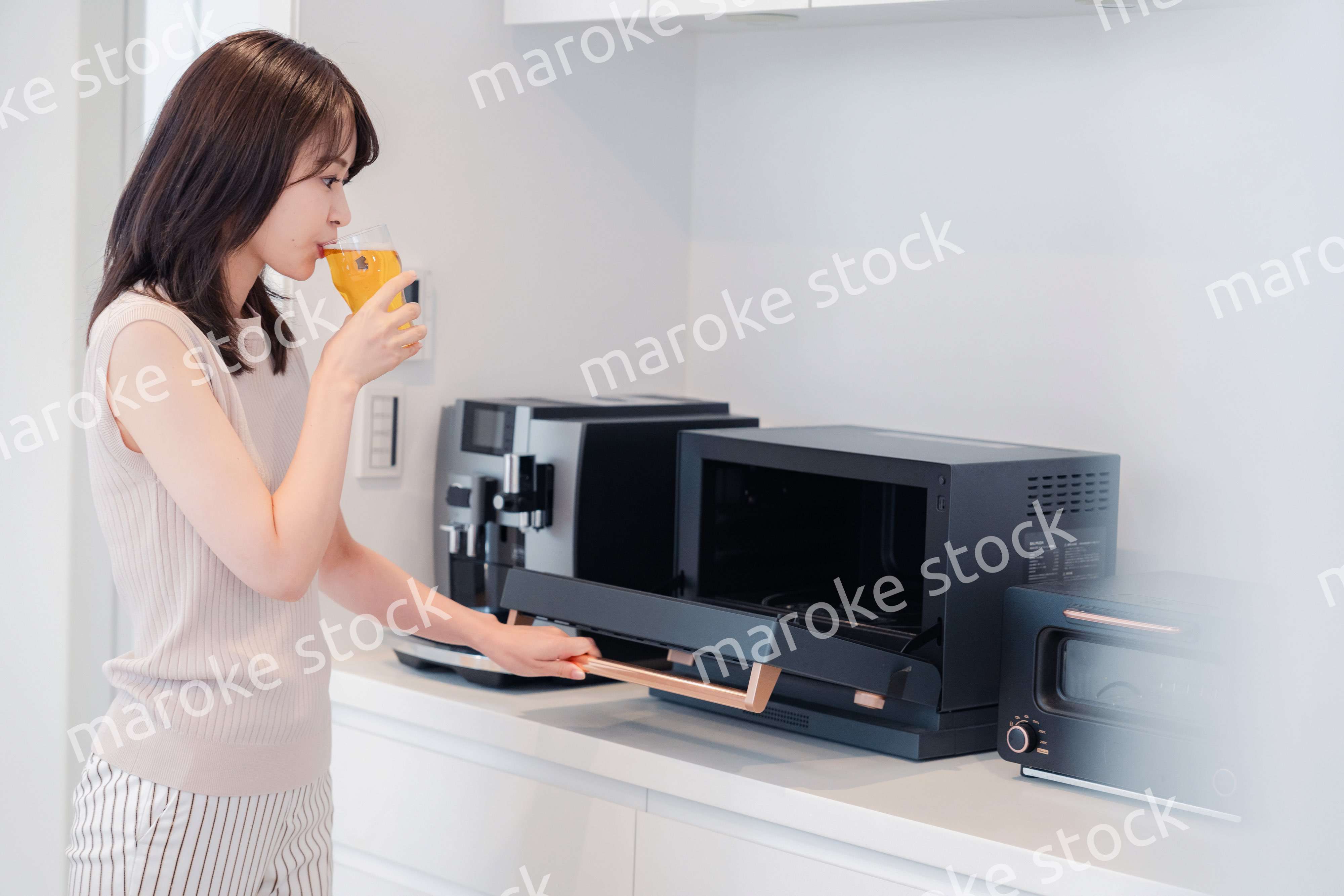 家事をしながらアルコールを飲む若い女性