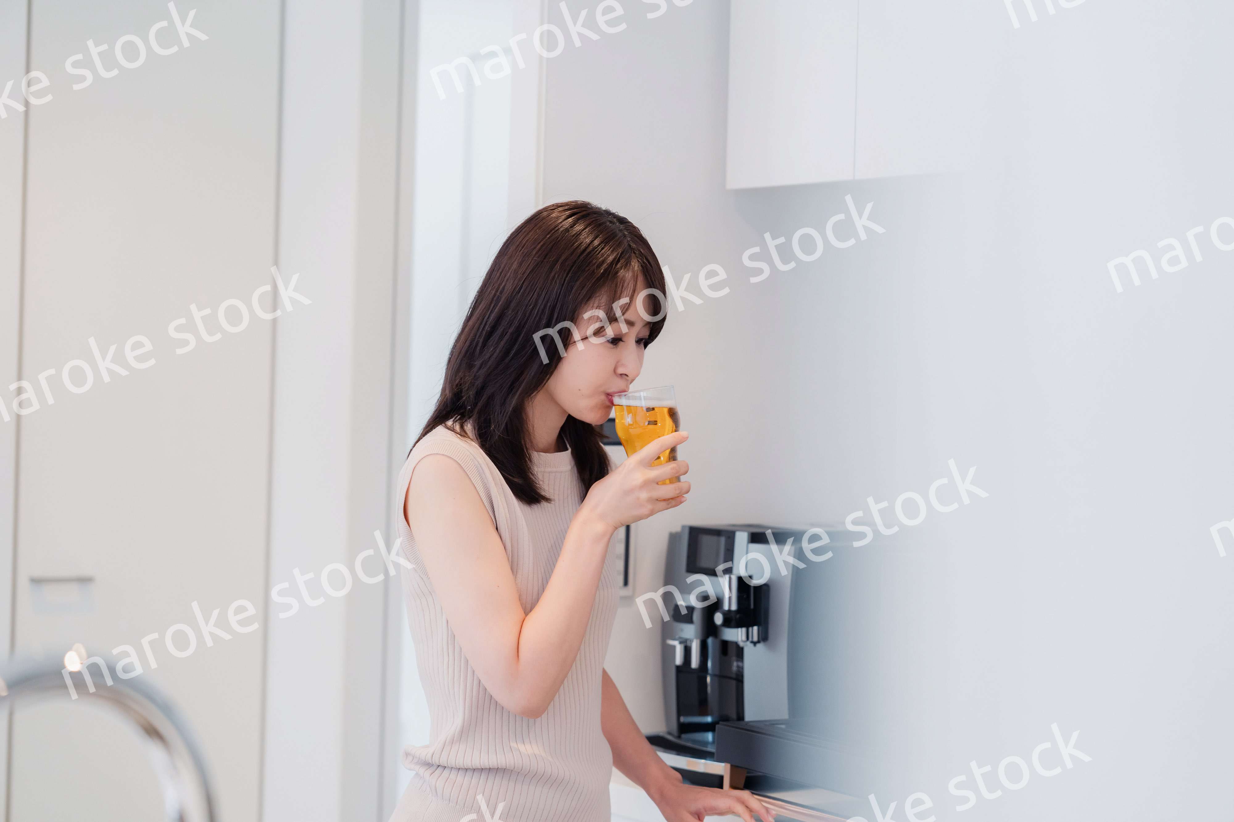 家事をしながらアルコールを飲む若い女性