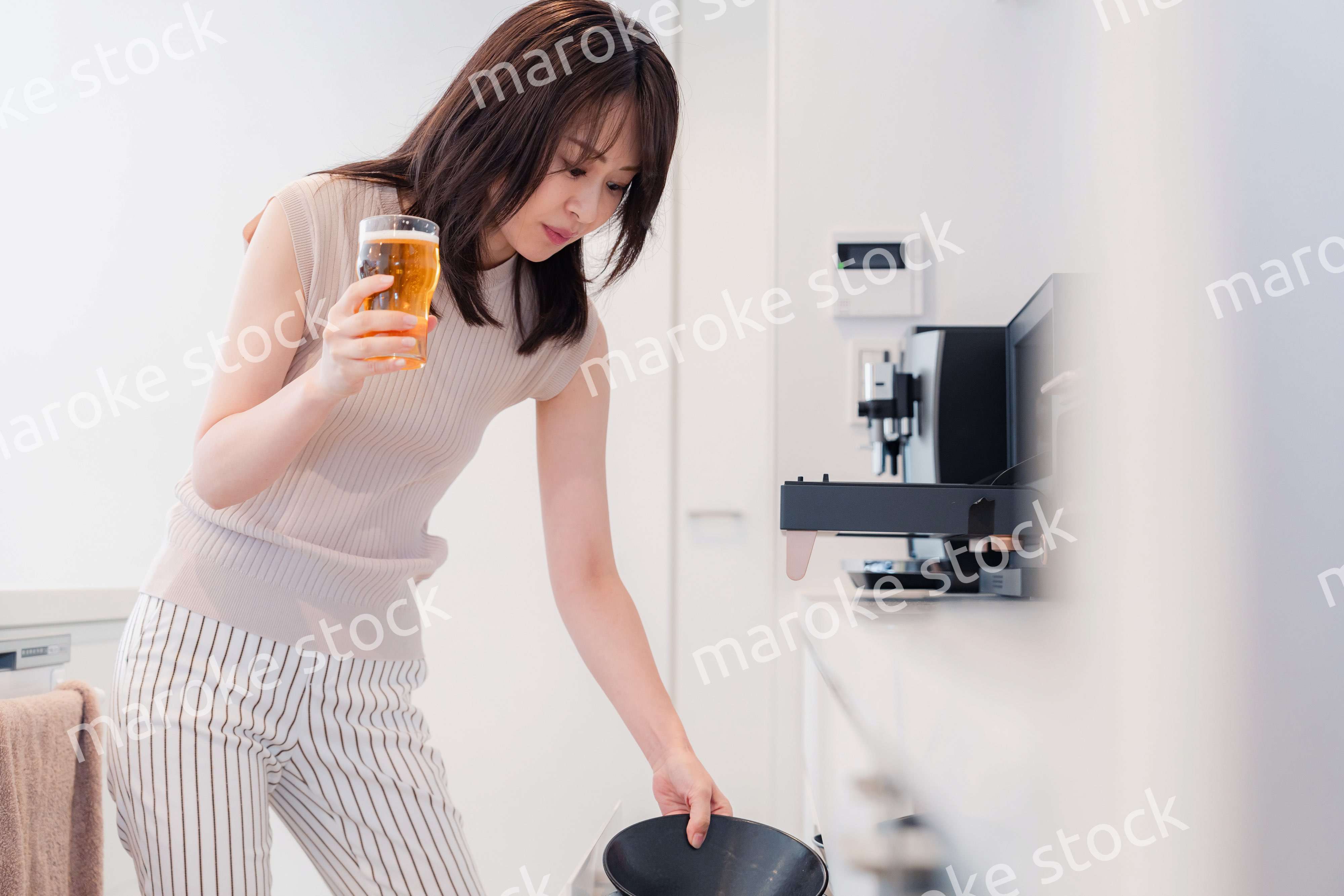 家事をしながらアルコールを飲む若い女性