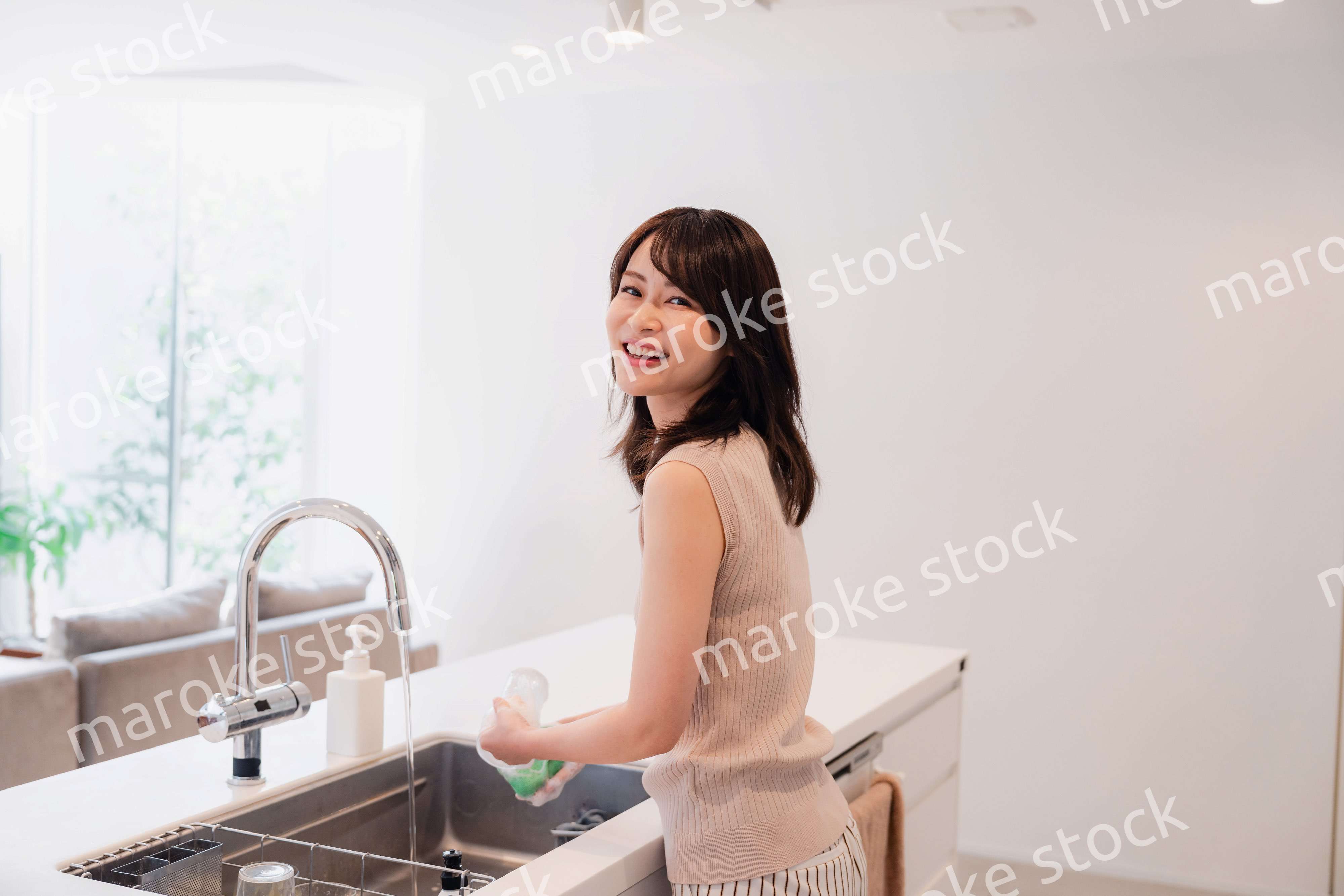 キッチンで洗い物をする若い女性