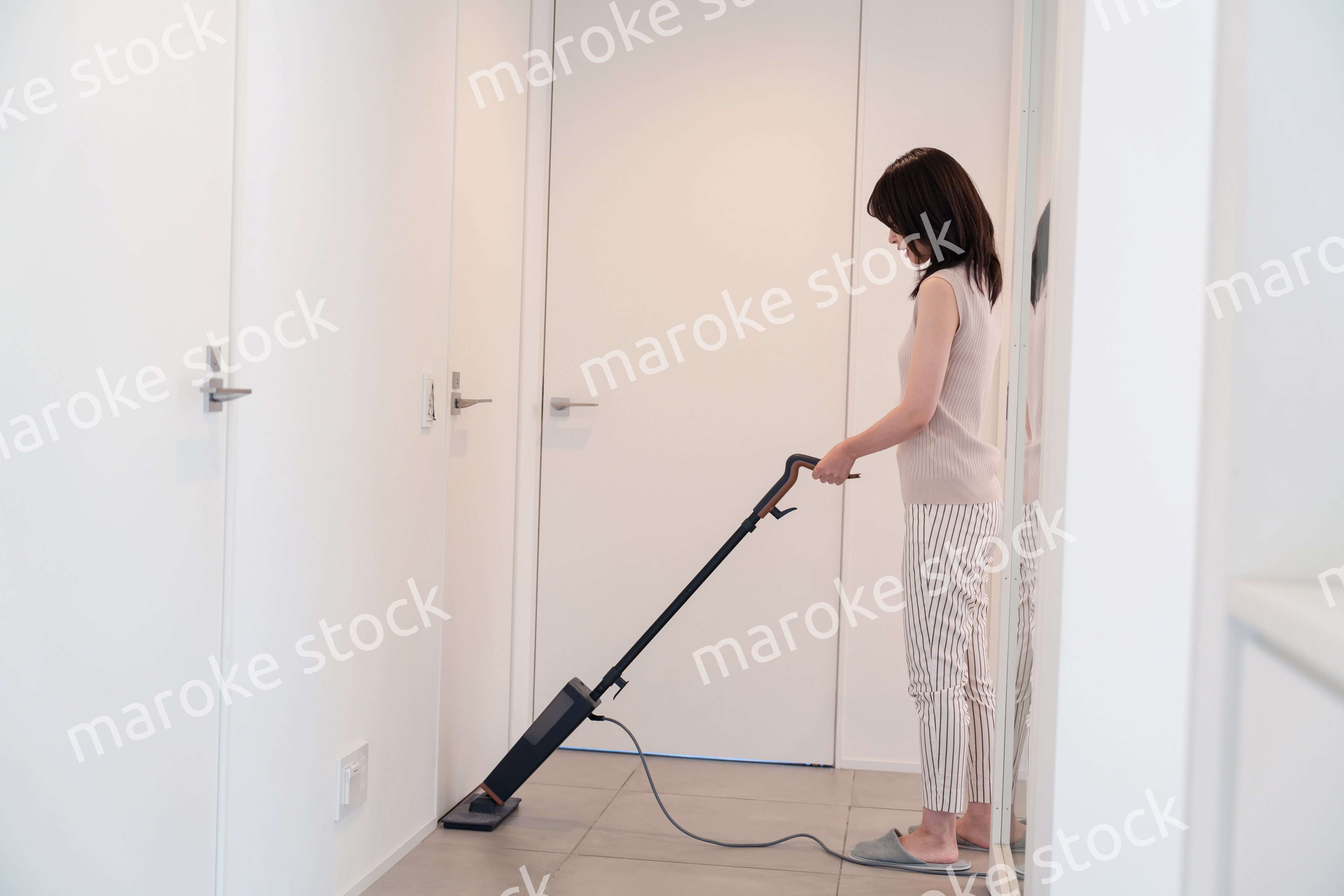 掃除機で家の掃除をする若い女性