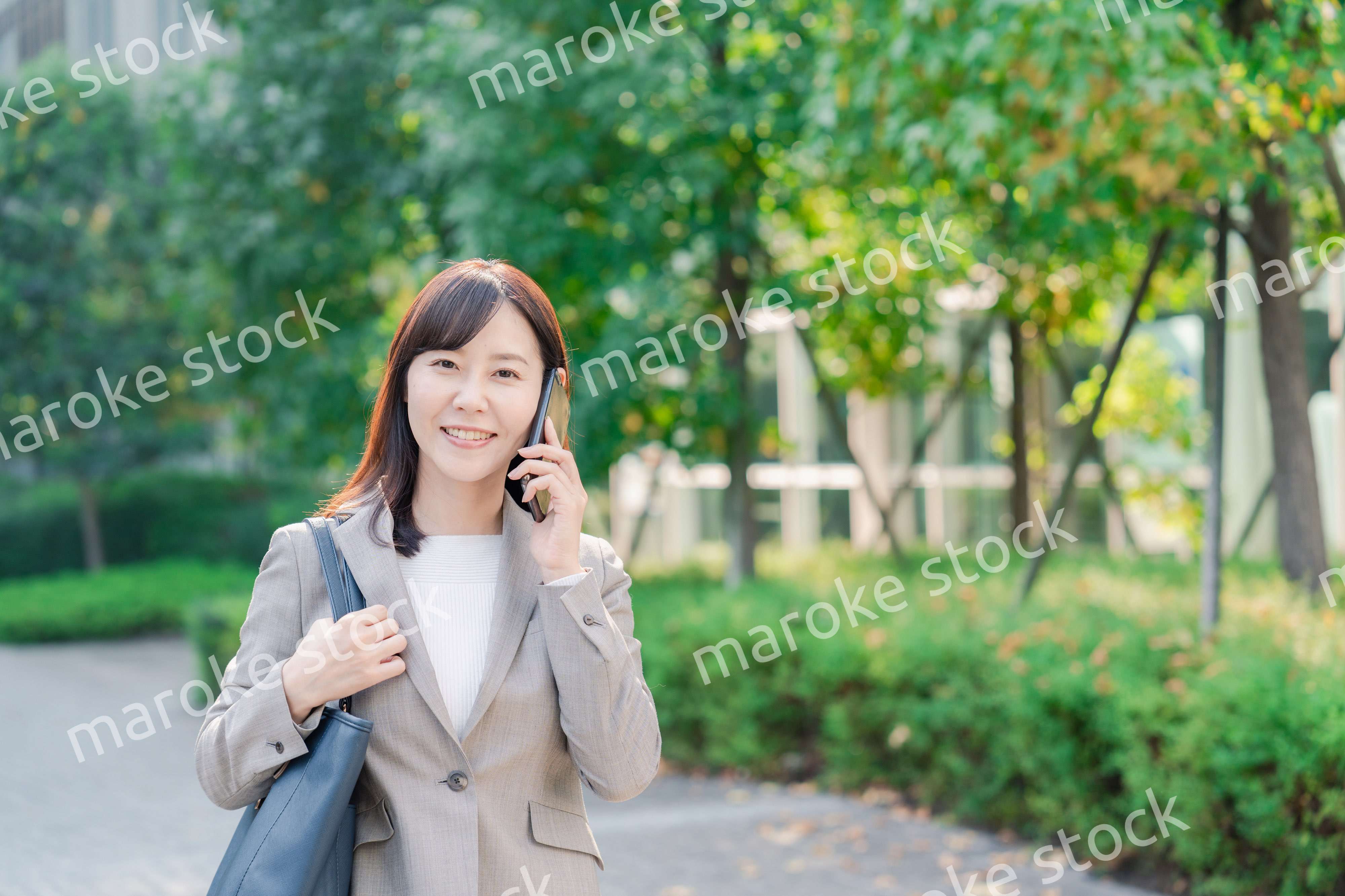 電話で話しながらビジネス街を歩くビジネスウーマン