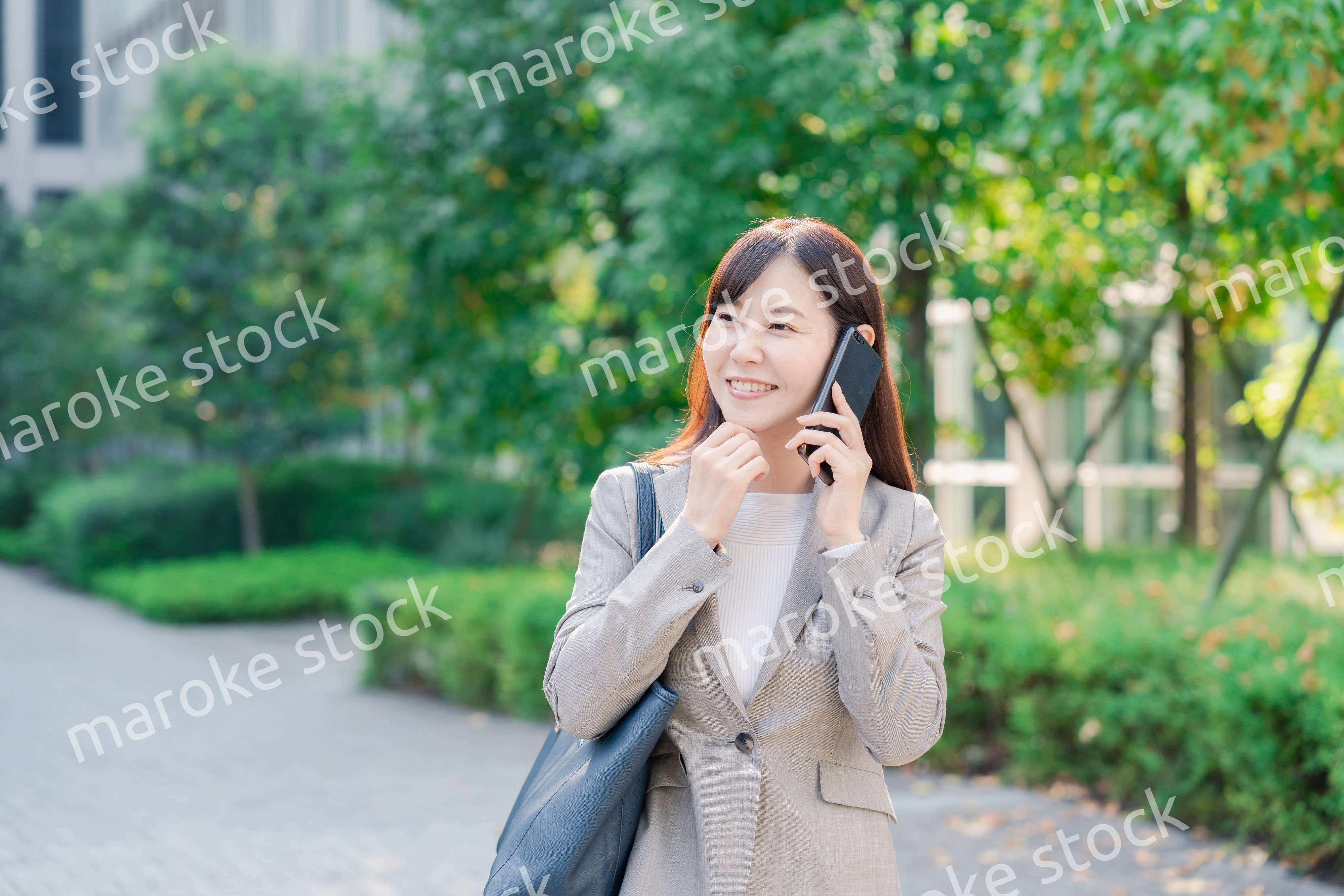 電話で話しながらビジネス街を歩くビジネスウーマン