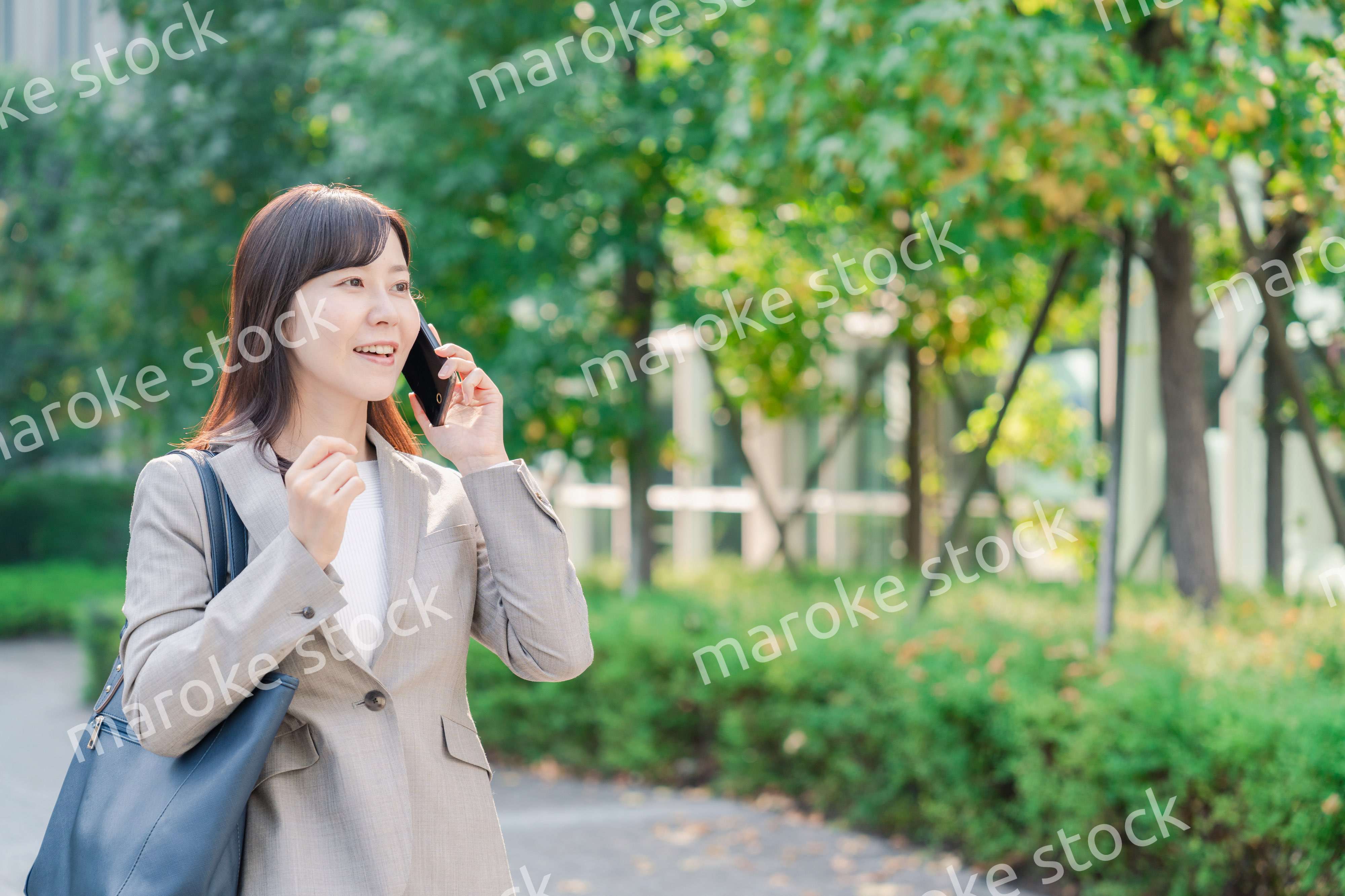 電話で話しながらビジネス街を歩くビジネスウーマン