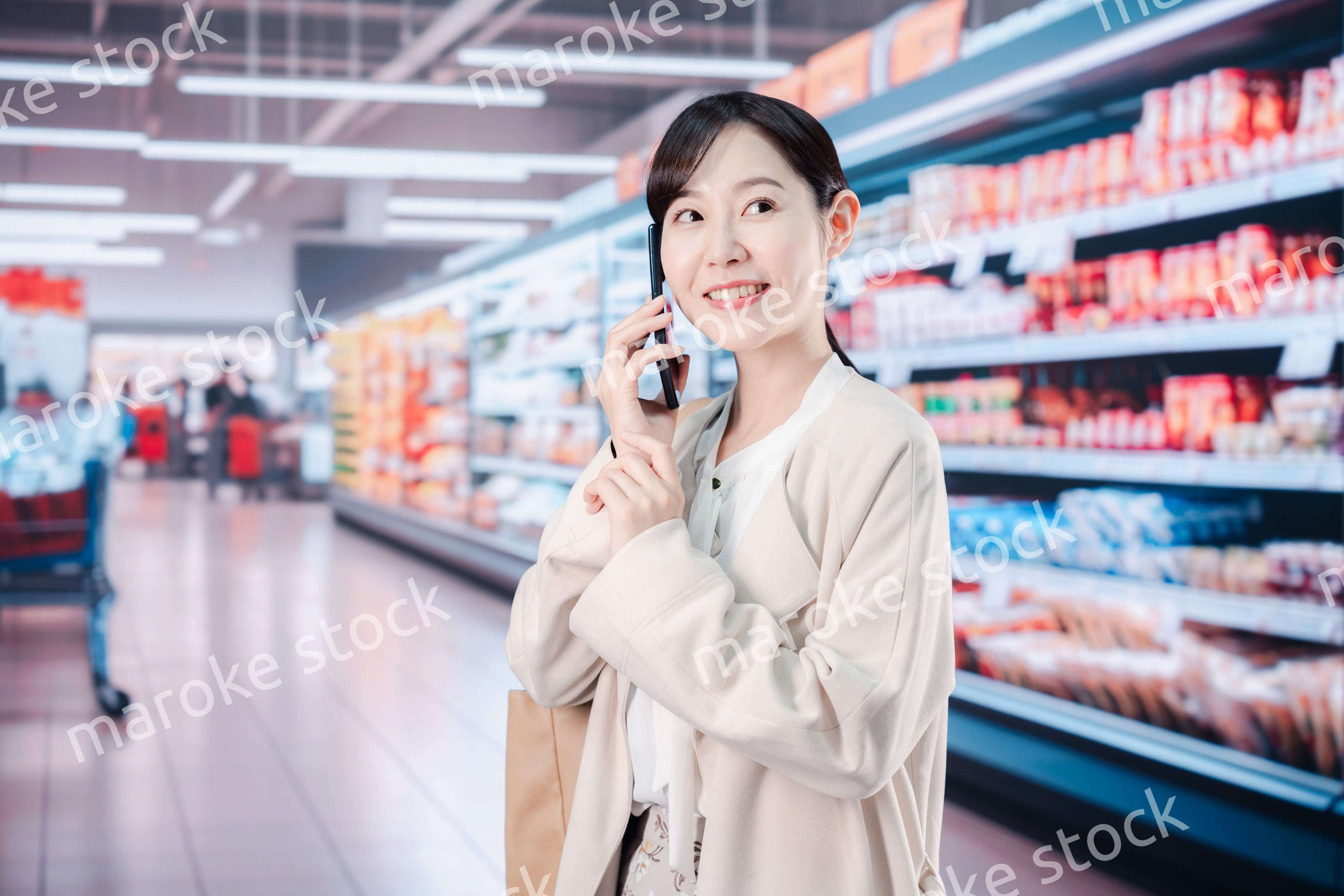 スマホを使いながらスーパーで買い物をする主婦