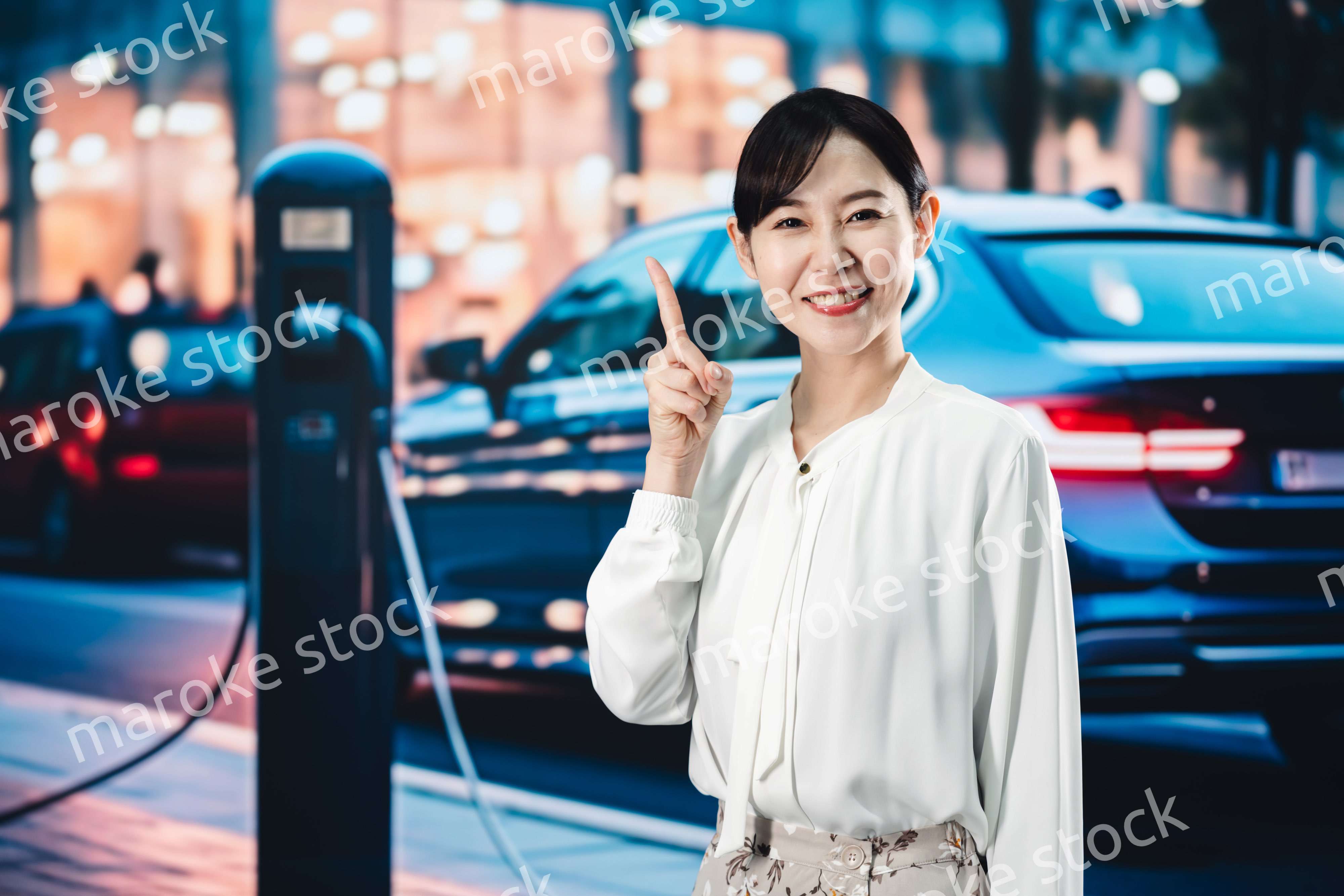 道路で電気自動車を充電する女性