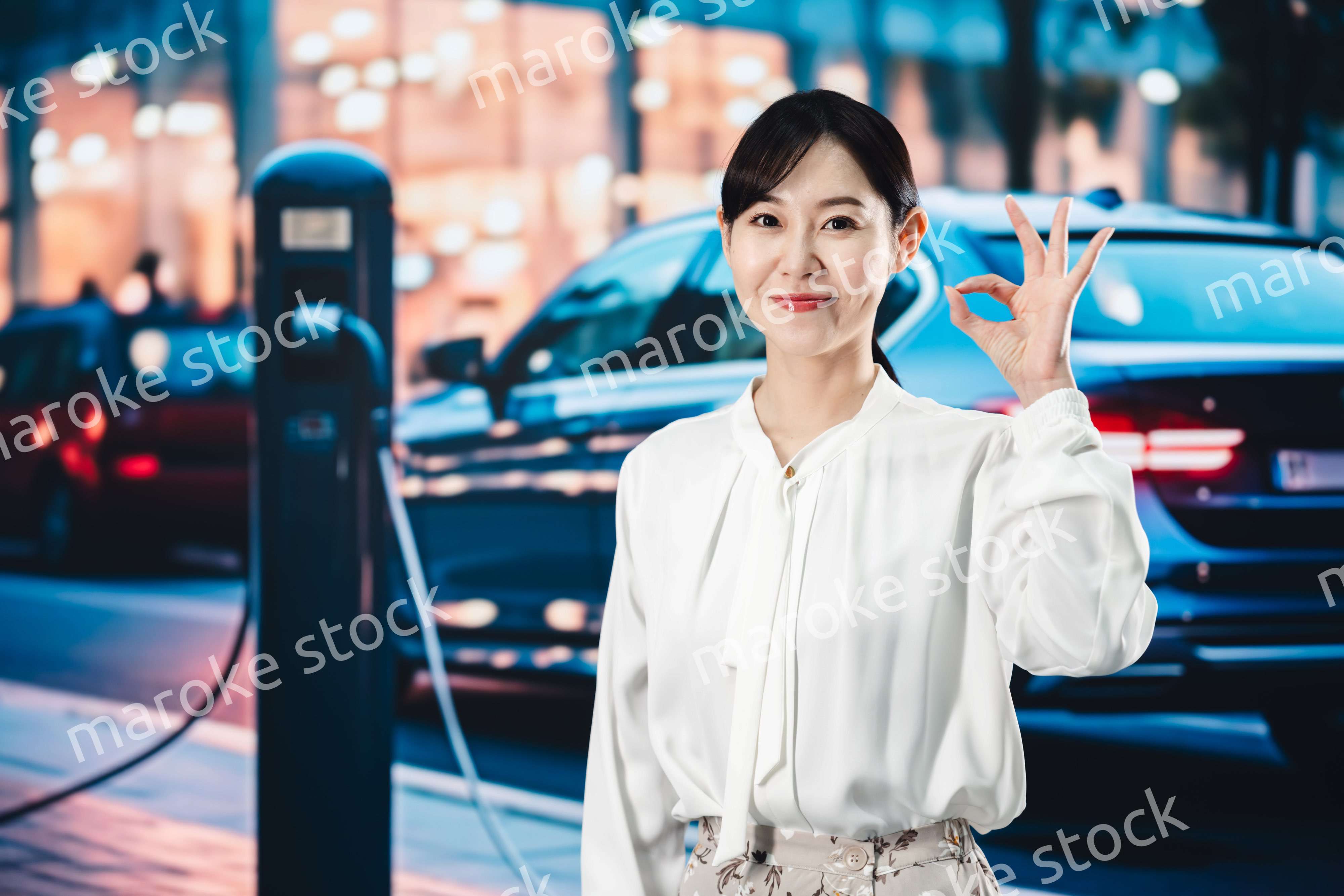 道路で電気自動車を充電する女性