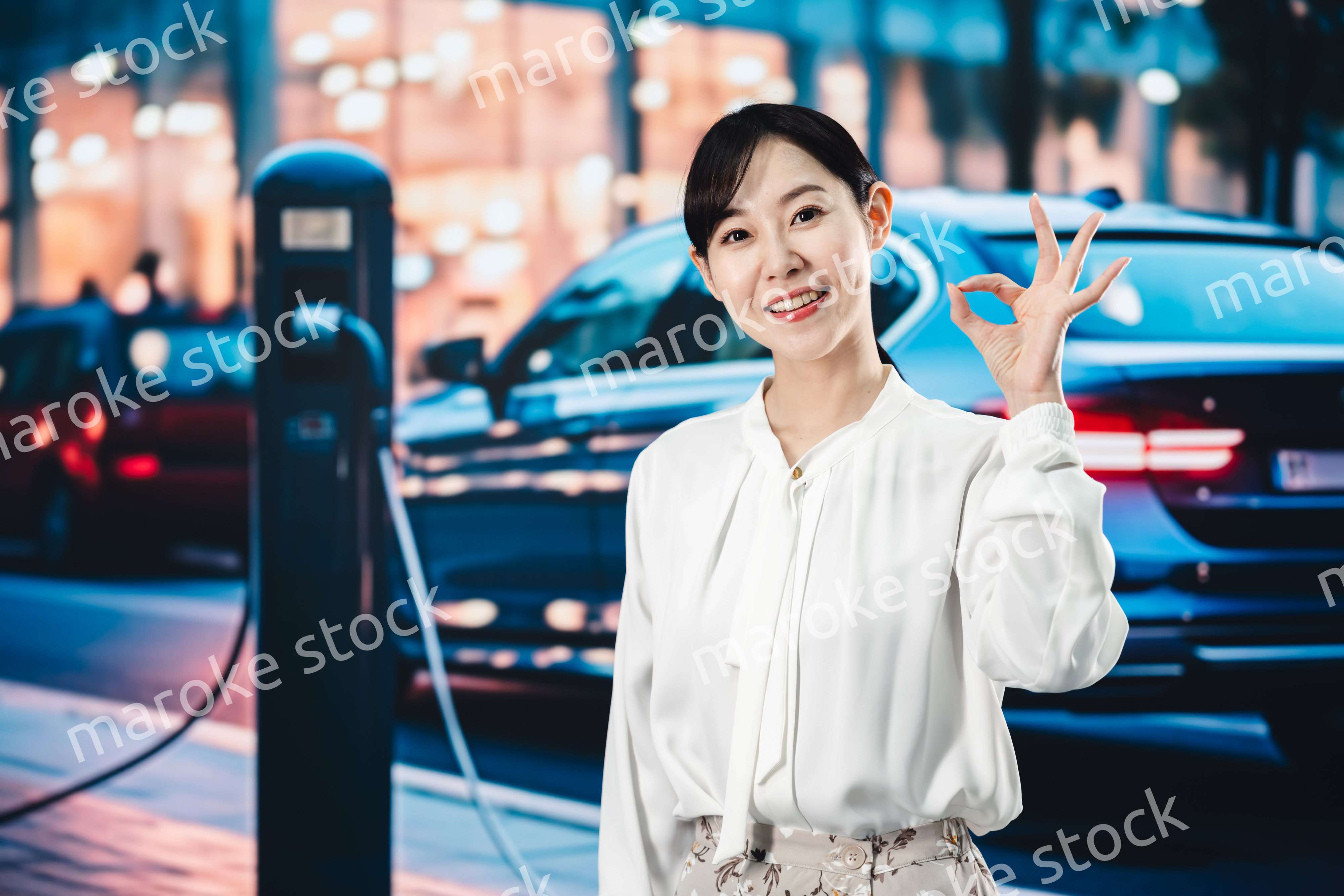 道路で電気自動車を充電する女性