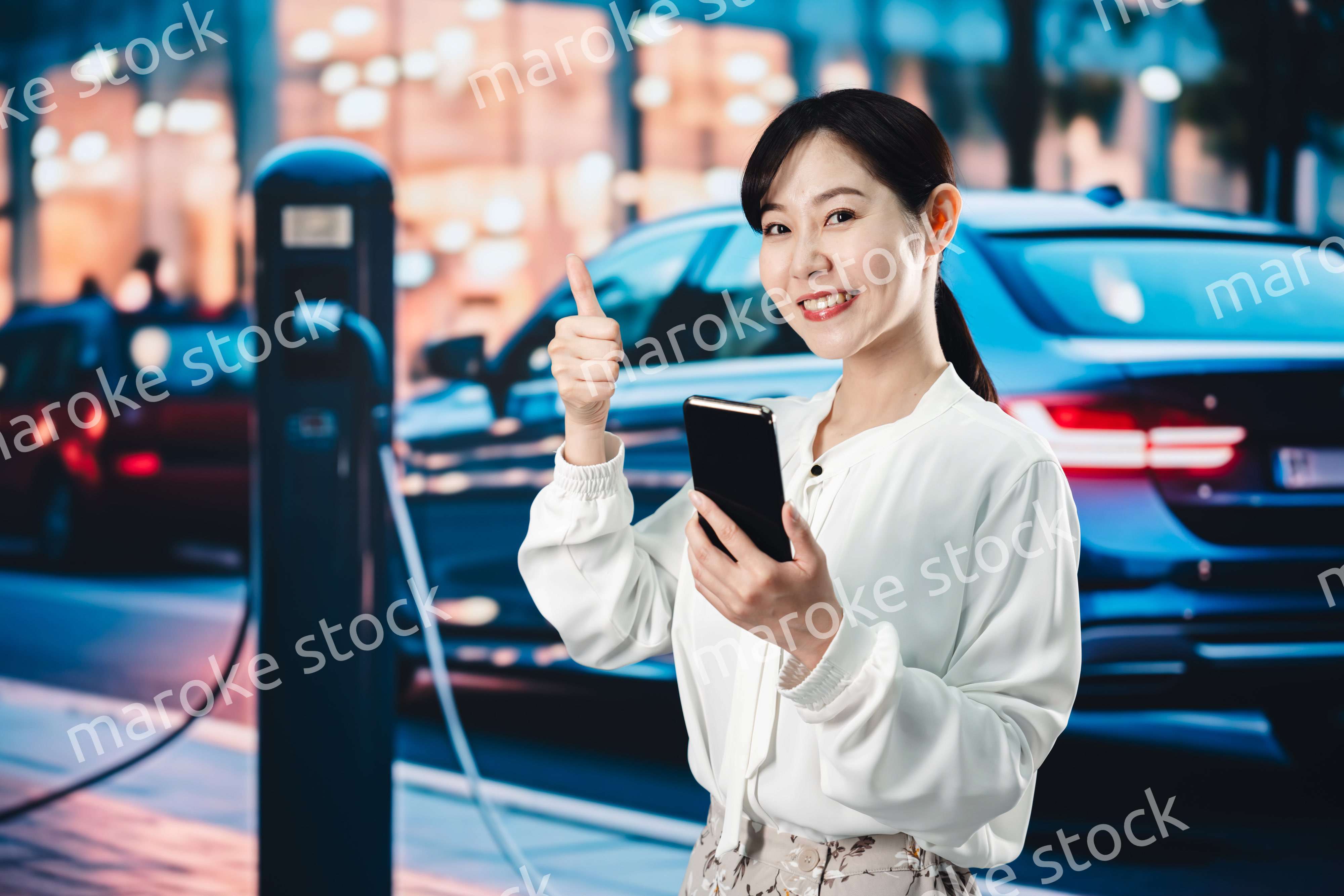道路で電気自動車を充電する女性