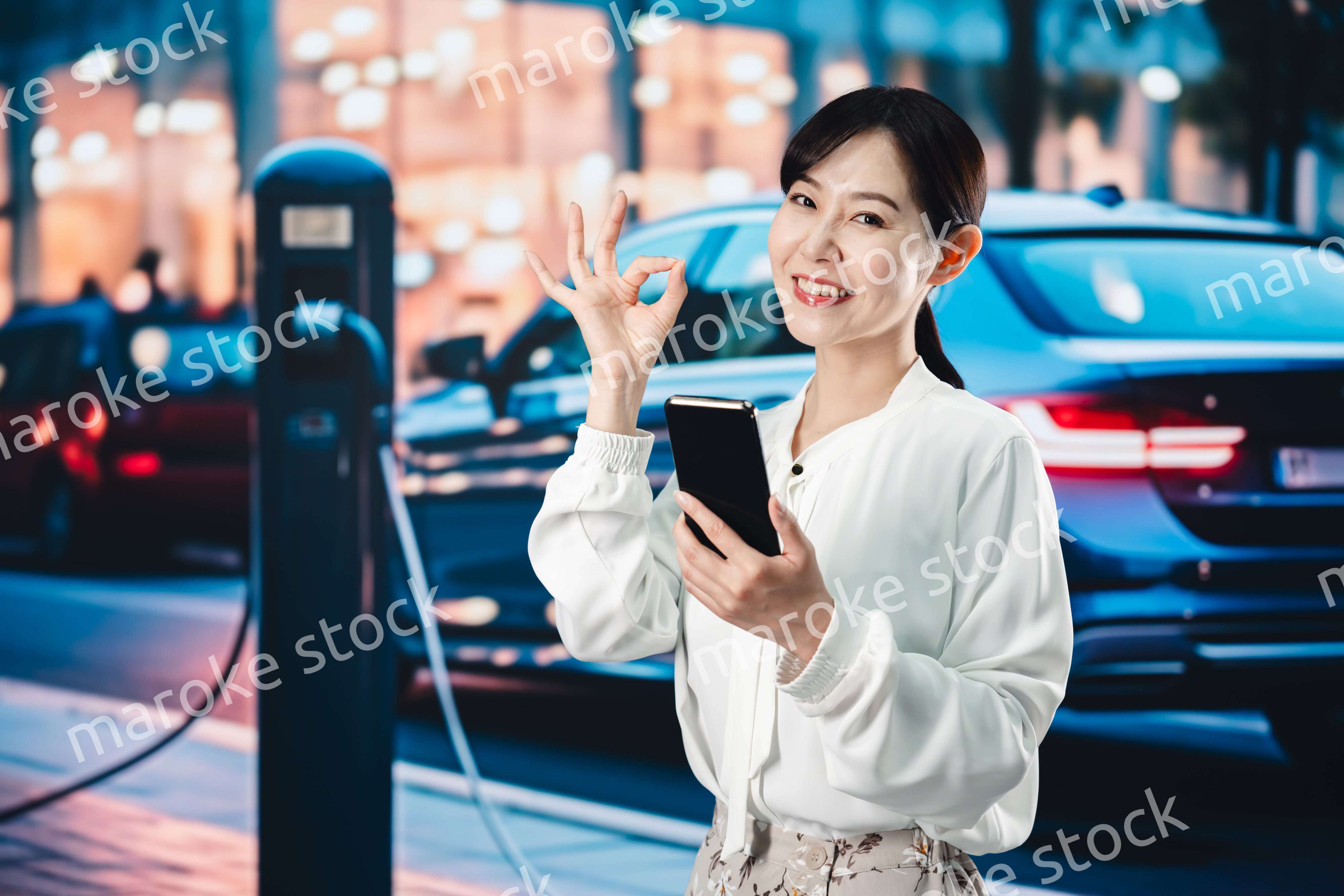 道路で電気自動車を充電する女性