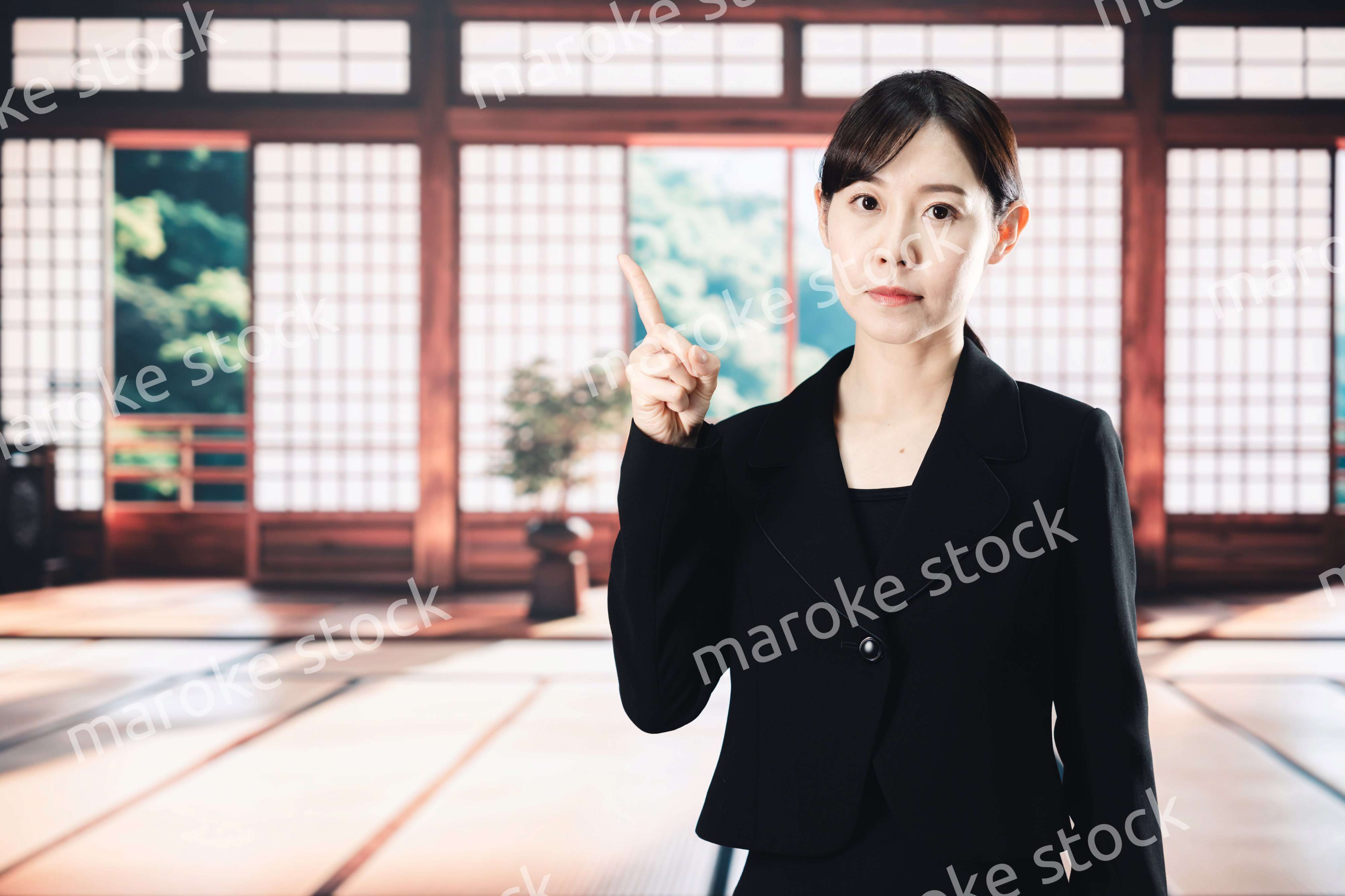 喪服で指を指しアドバイスをする女性
