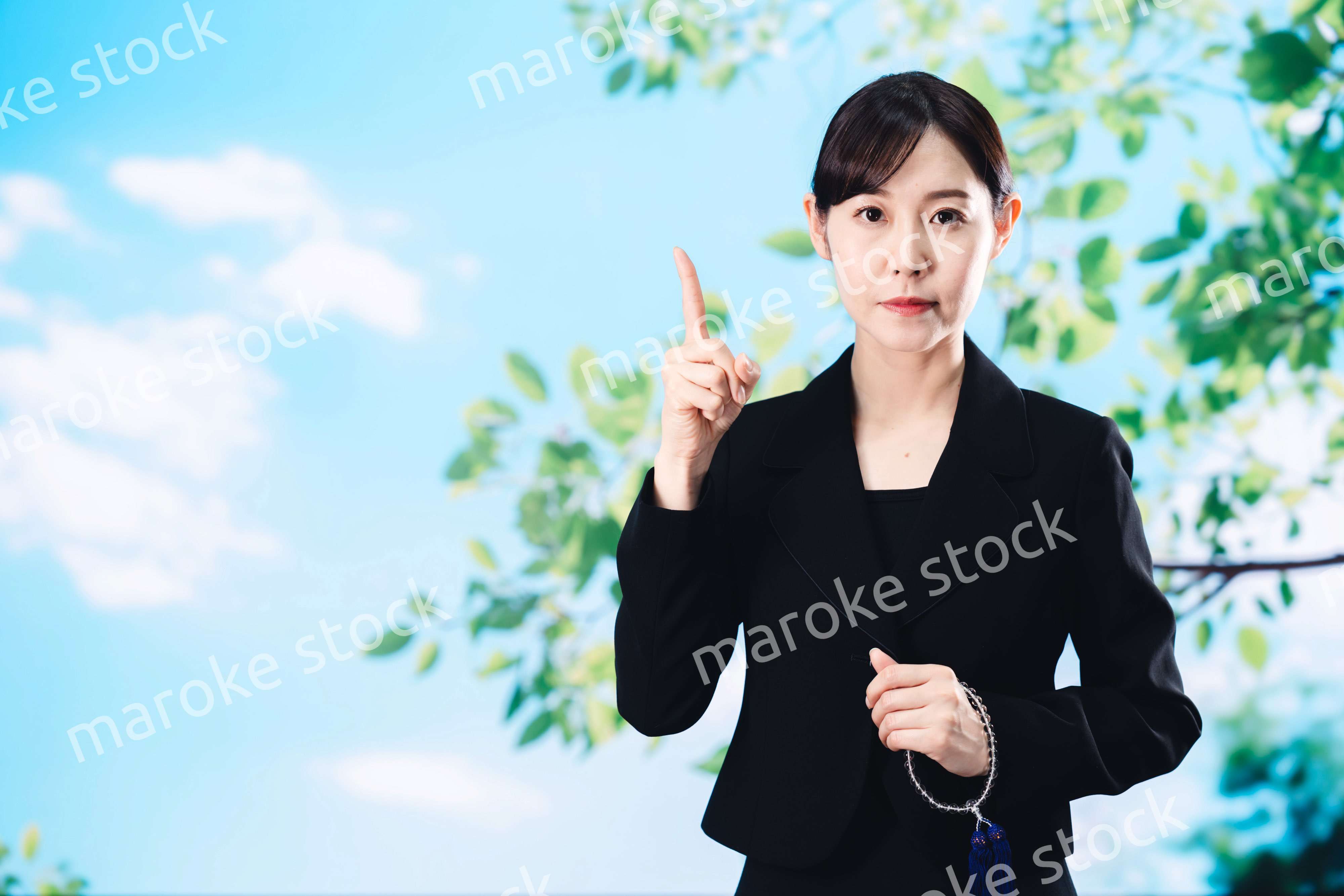 喪服で指を指しアドバイスをする女性