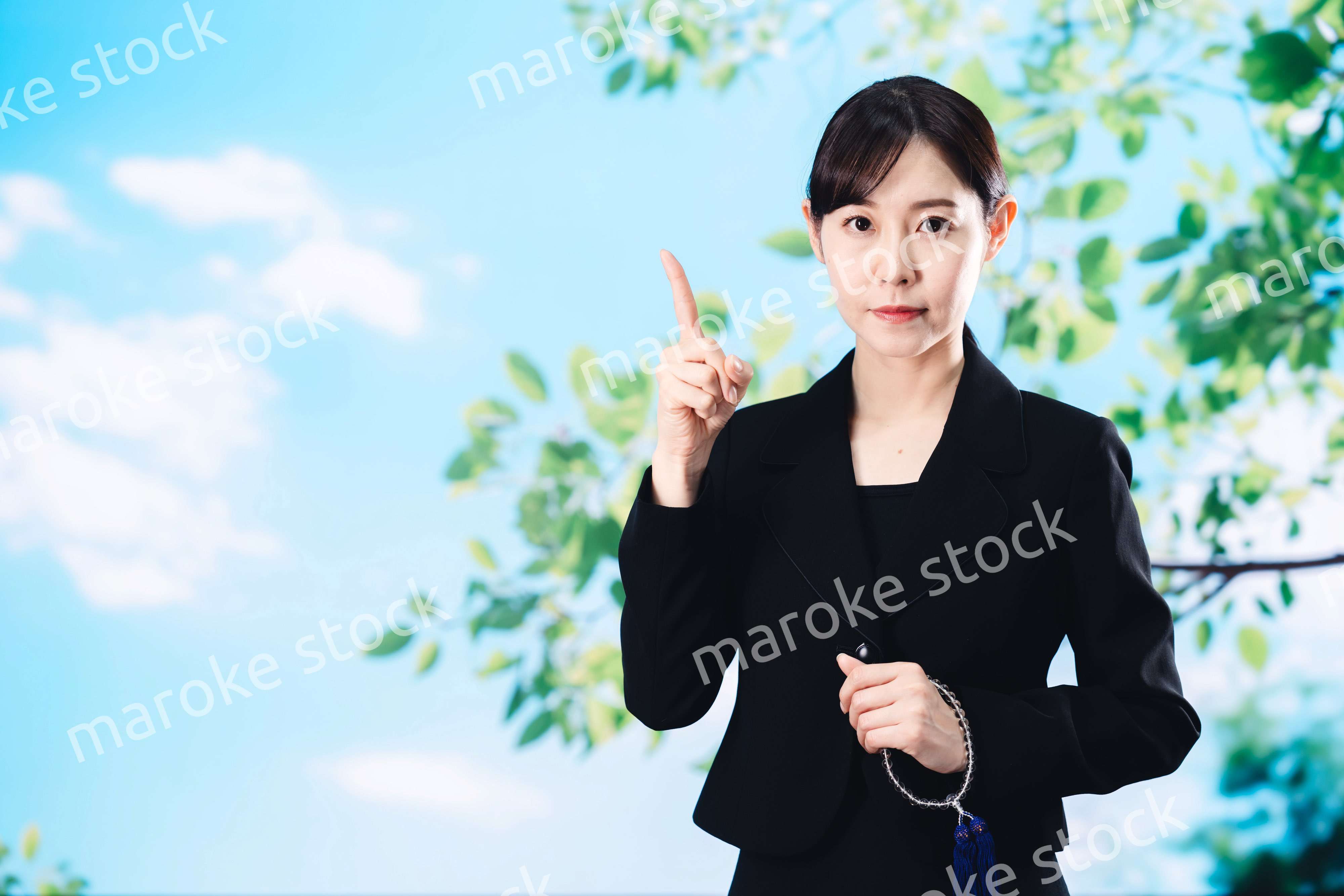 喪服で指を指しアドバイスをする女性