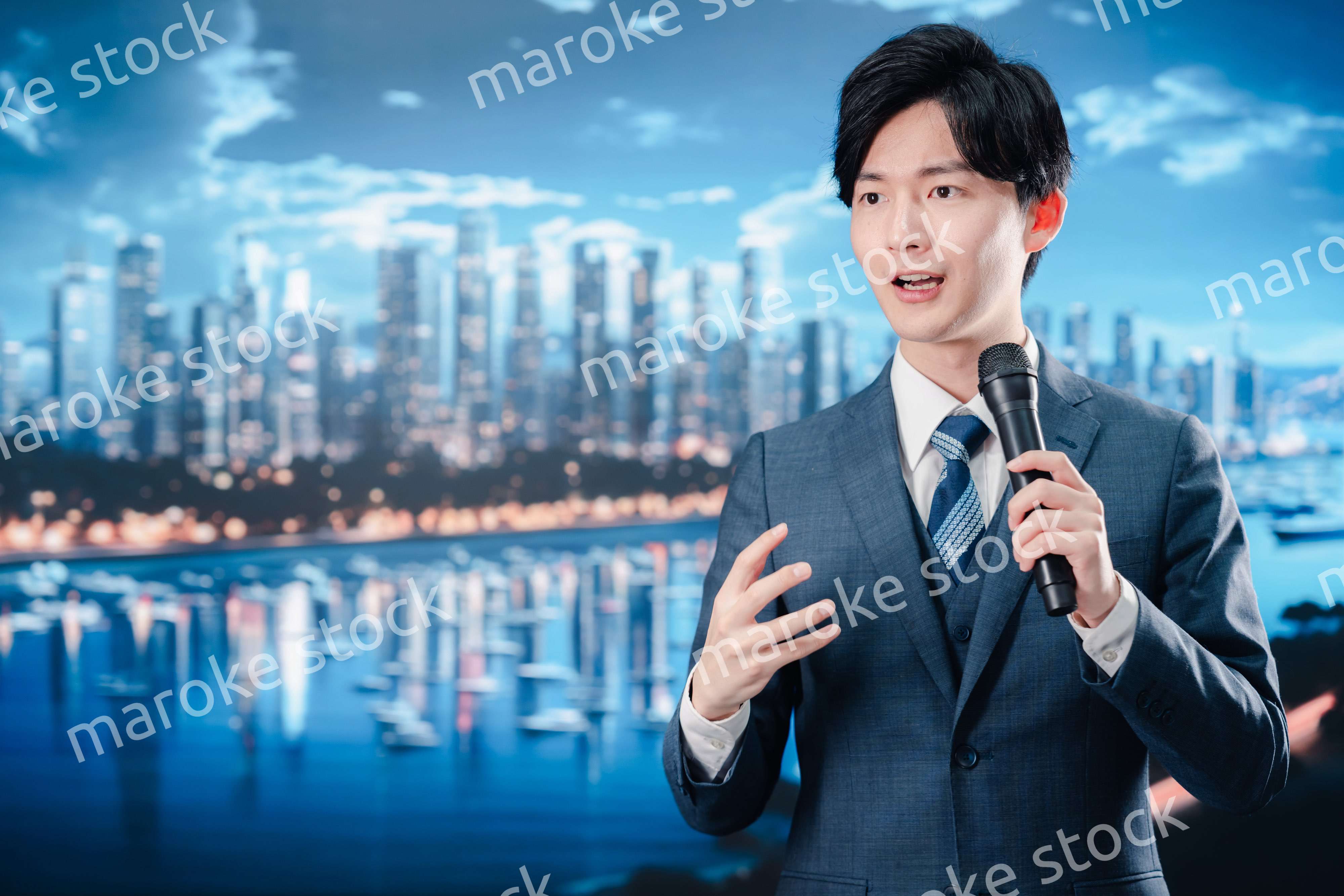 野外でマイクを使って話すスーツを着た男性