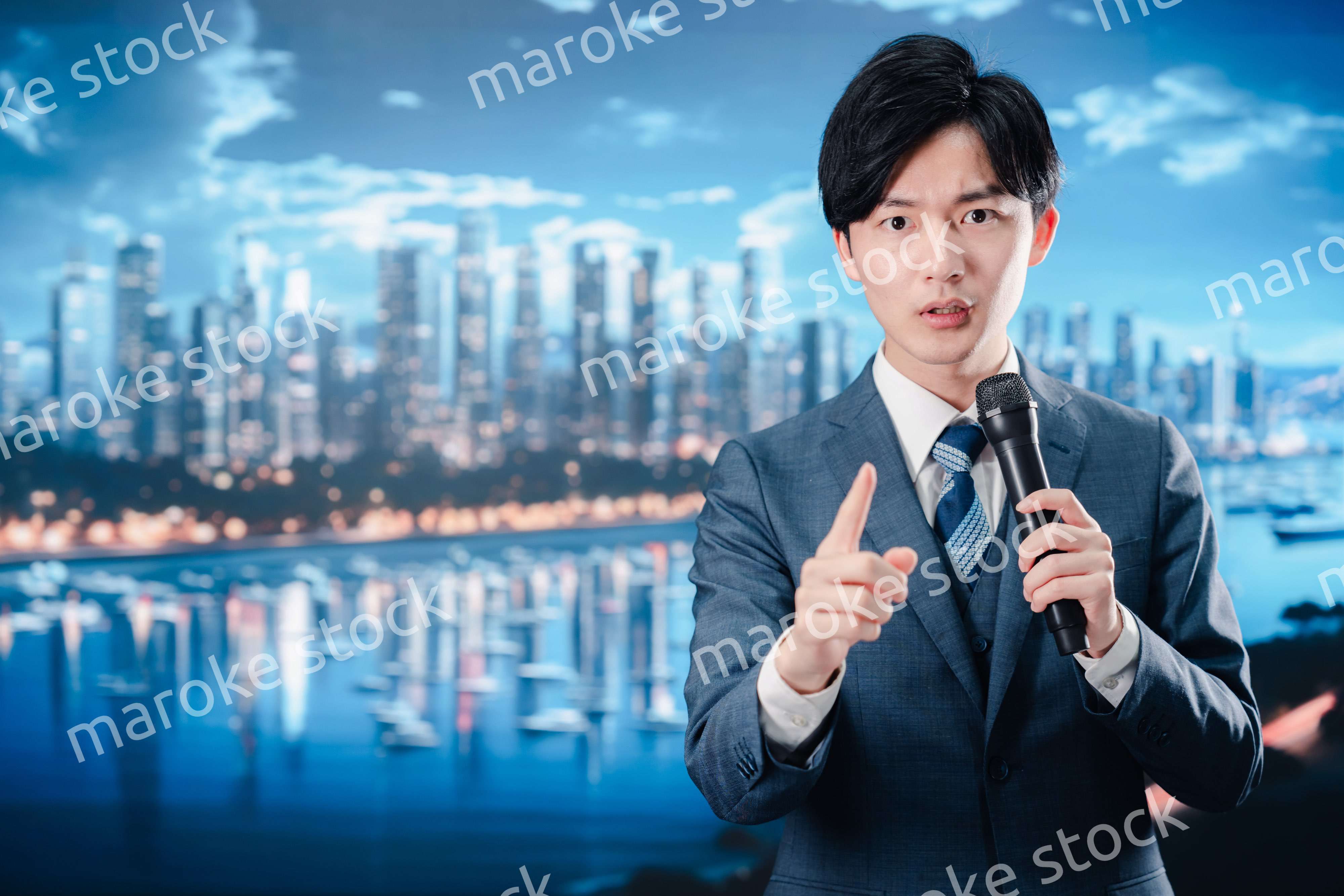 野外でマイクを使って話すスーツを着た男性