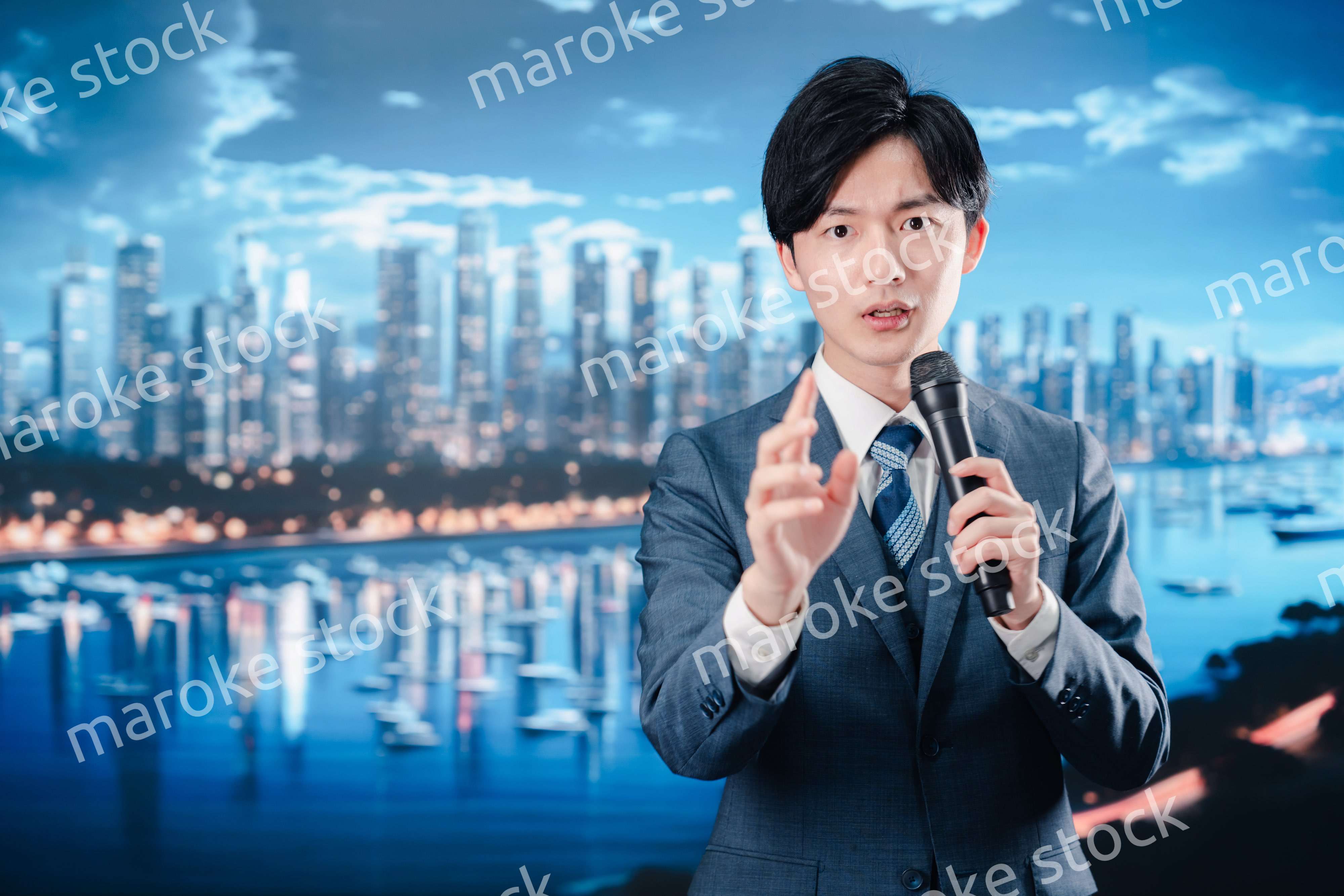 野外でマイクを使って話すスーツを着た男性