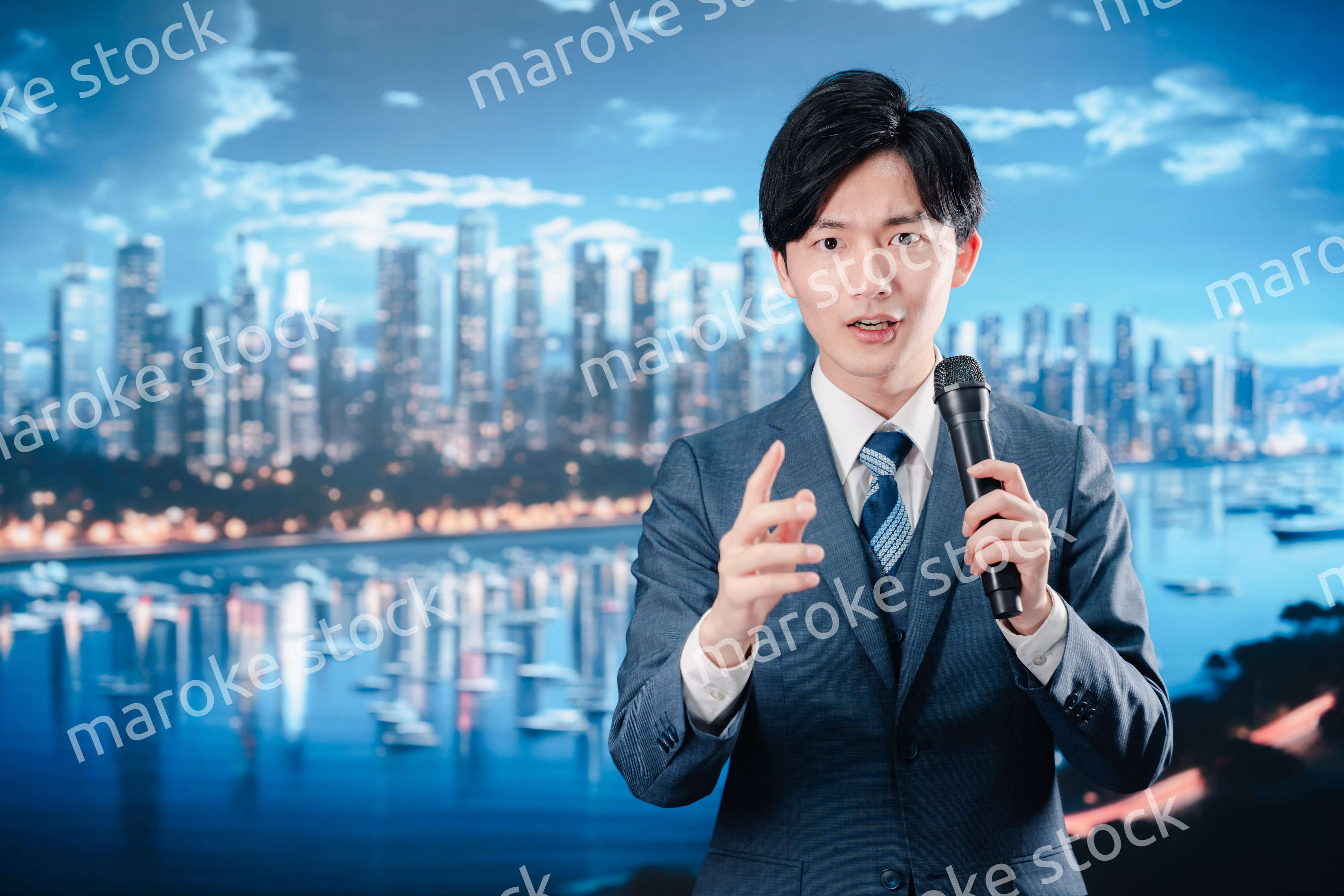 野外でマイクを使って話すスーツを着た男性