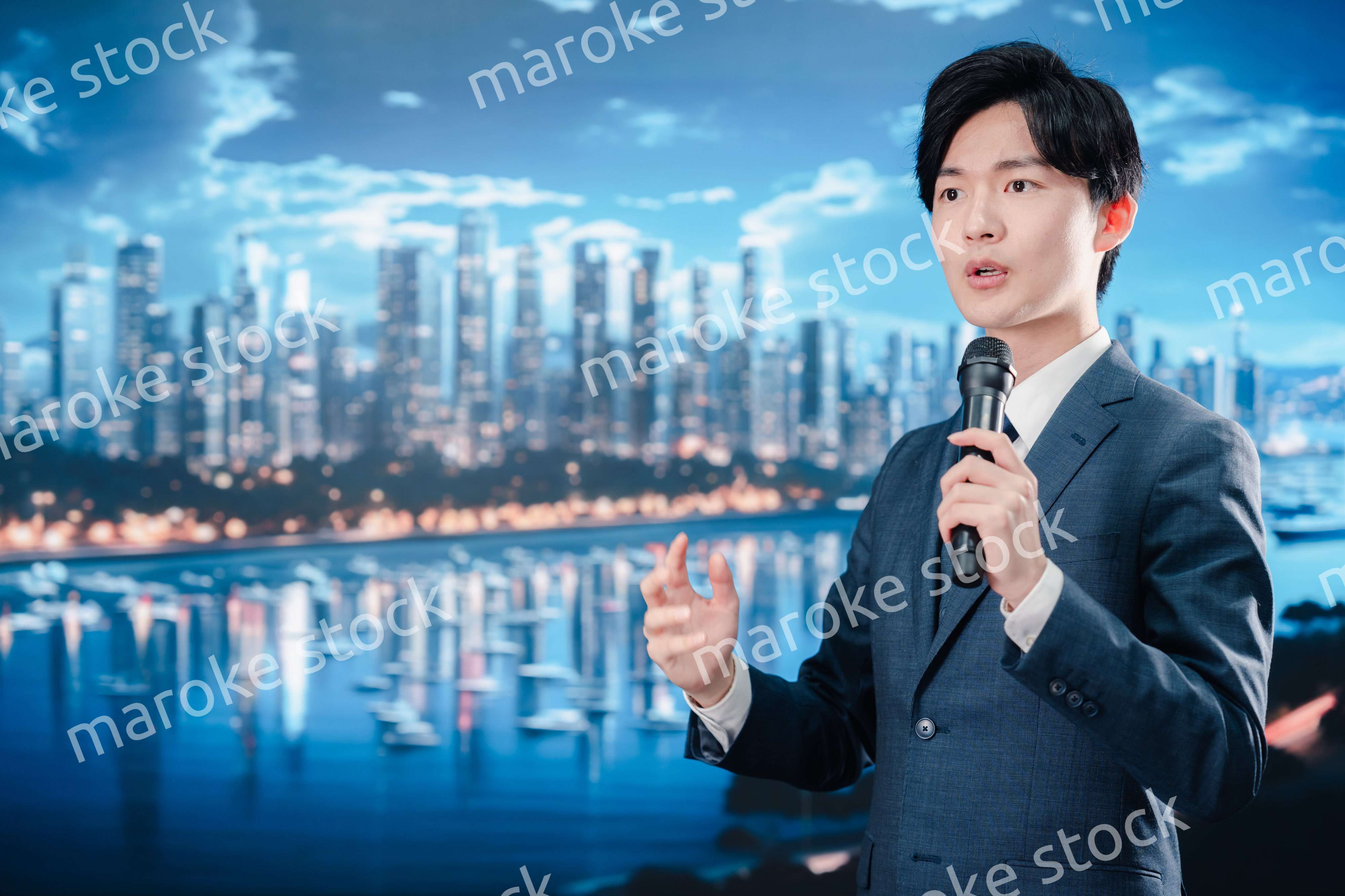 野外でマイクを使って話すスーツを着た男性