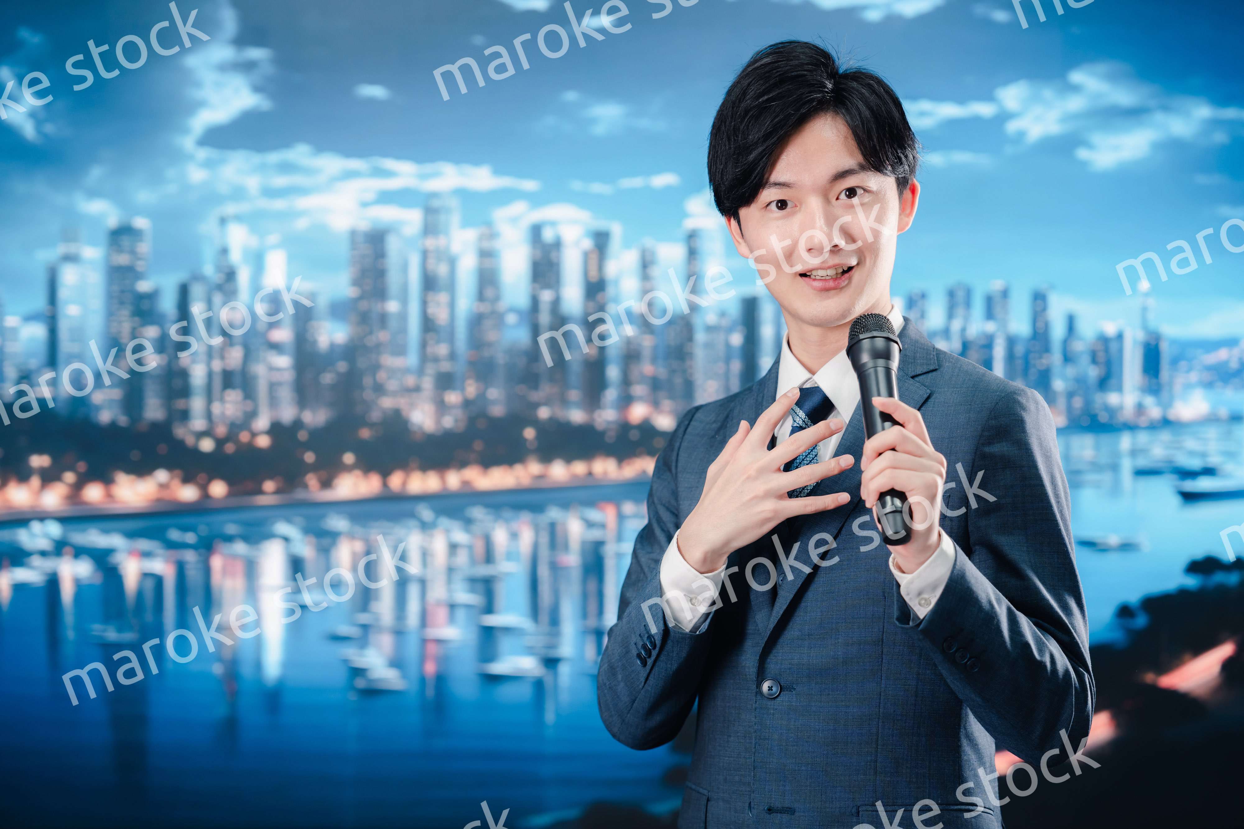 野外でマイクを使って話すスーツを着た男性