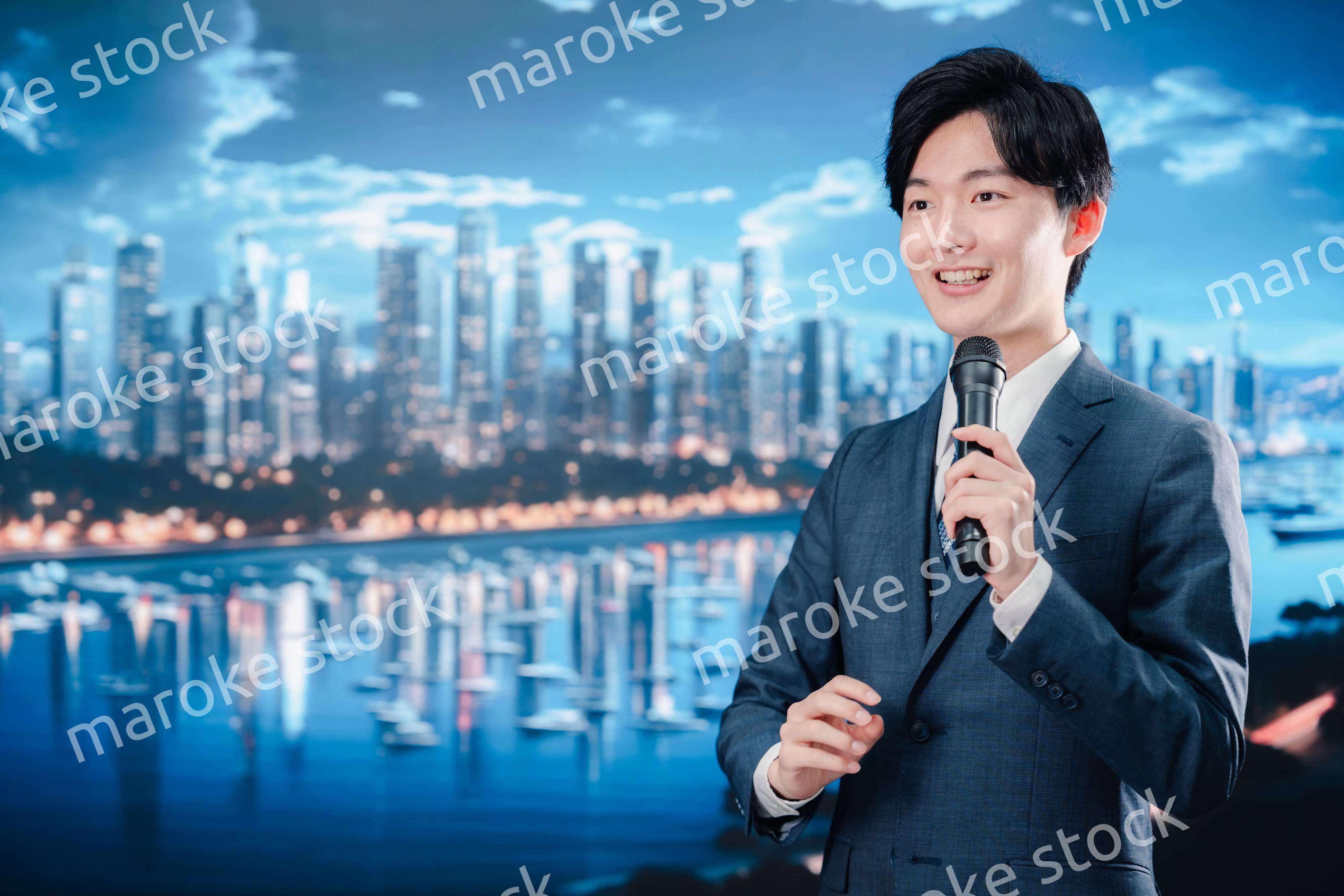 野外でマイクを使って話すスーツを着た男性