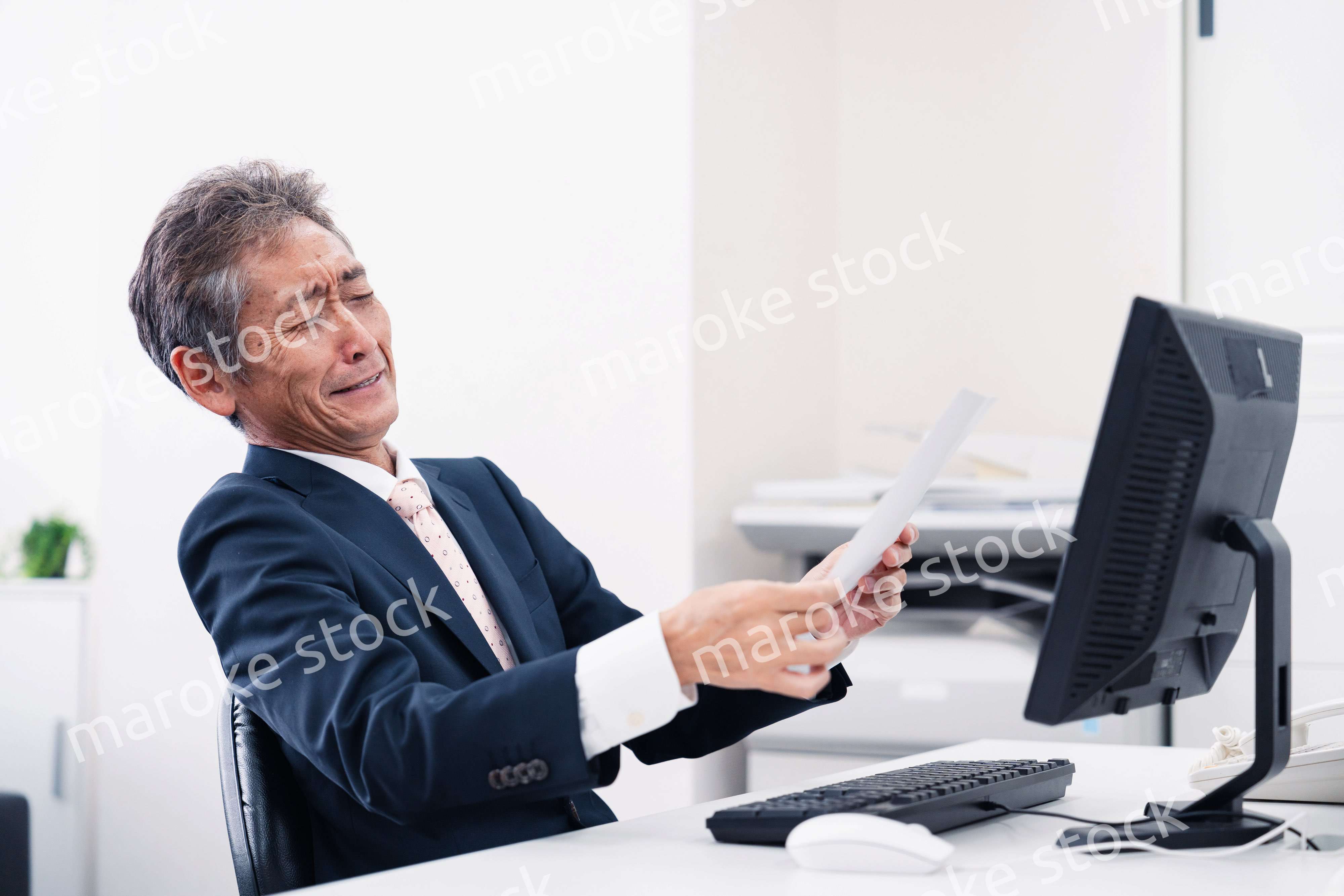 老眼で書類が見づらい高齢のビジネスマン