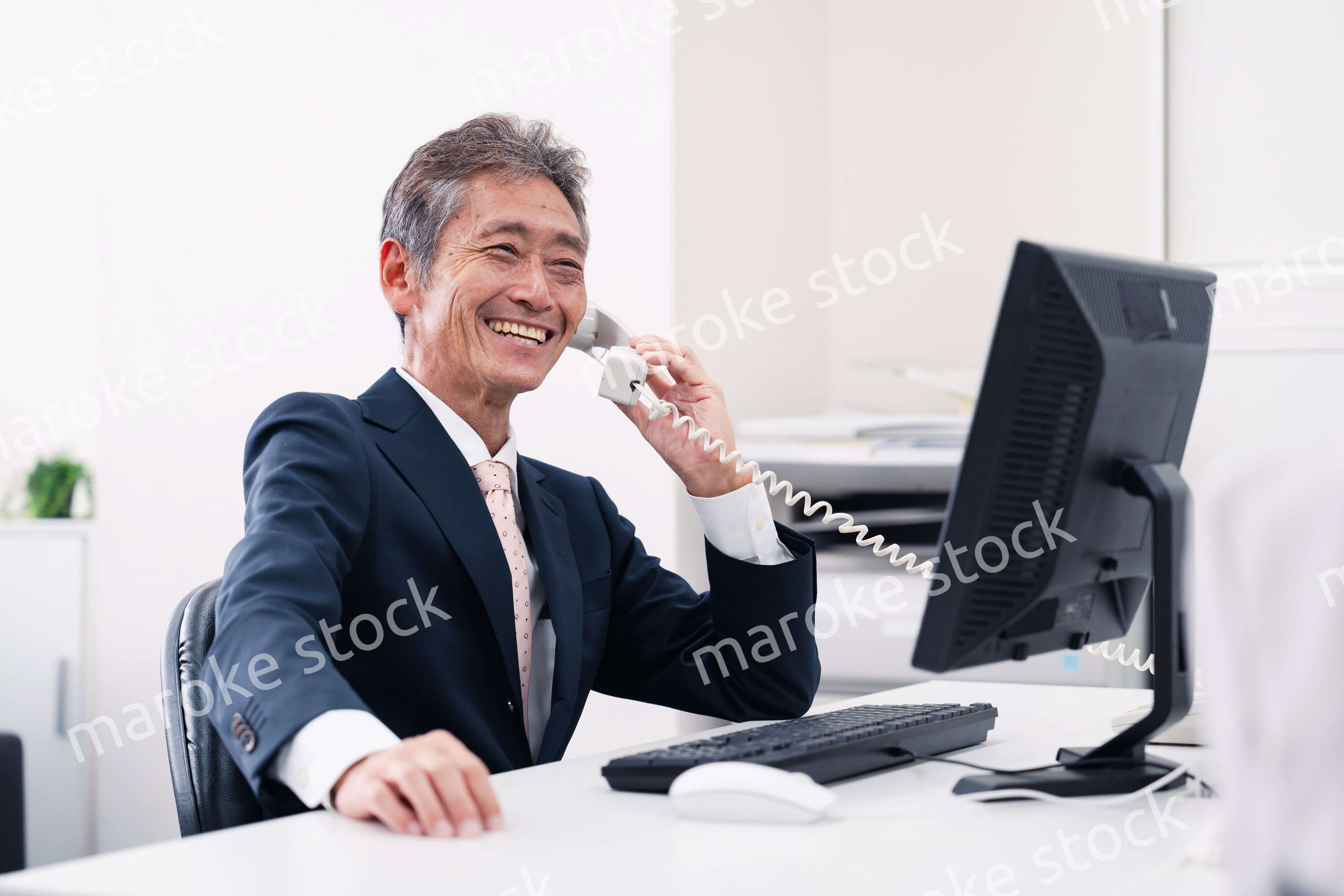 笑顔で電話をするミドルマネジメントの男性