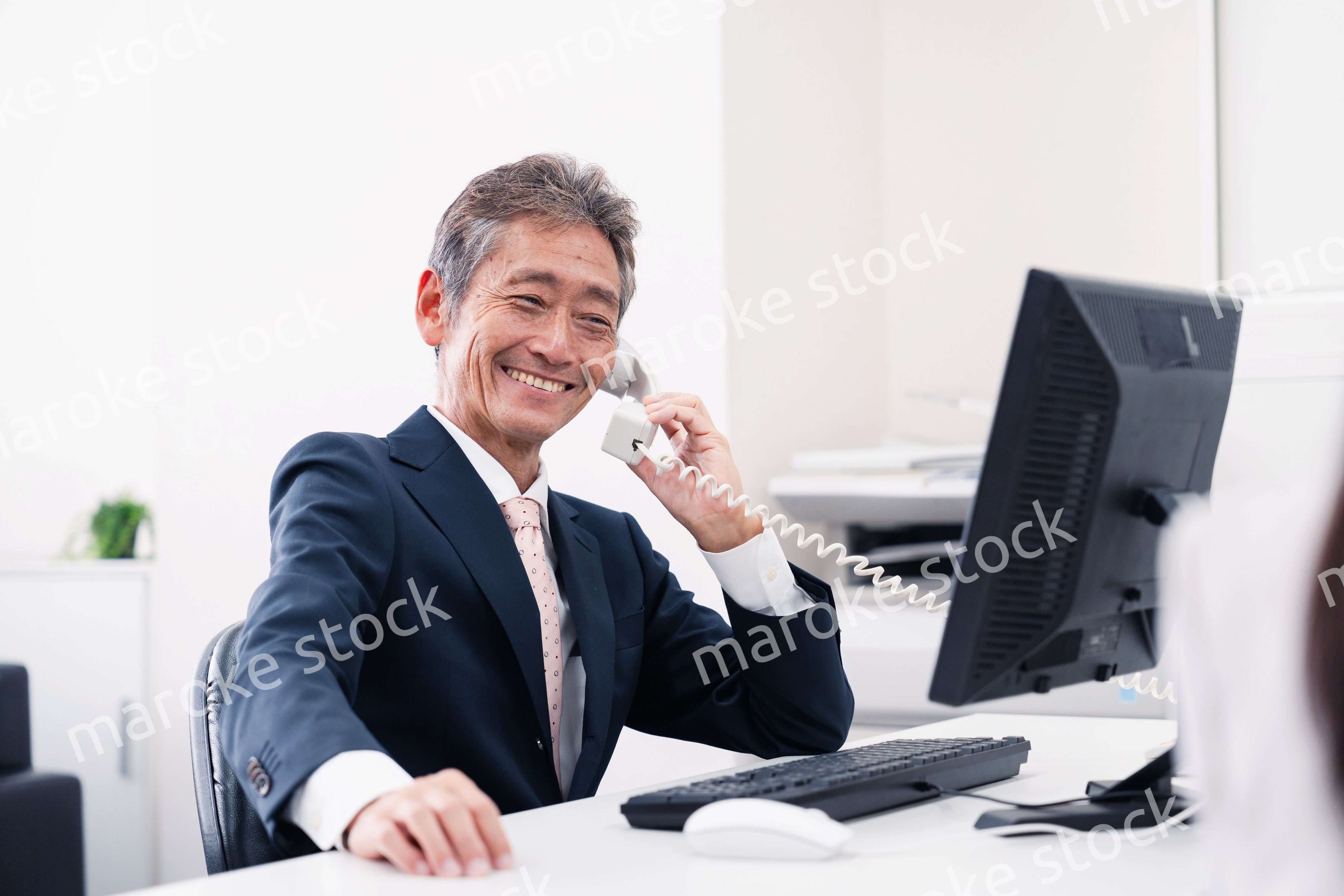 笑顔で電話をするミドルマネジメントの男性