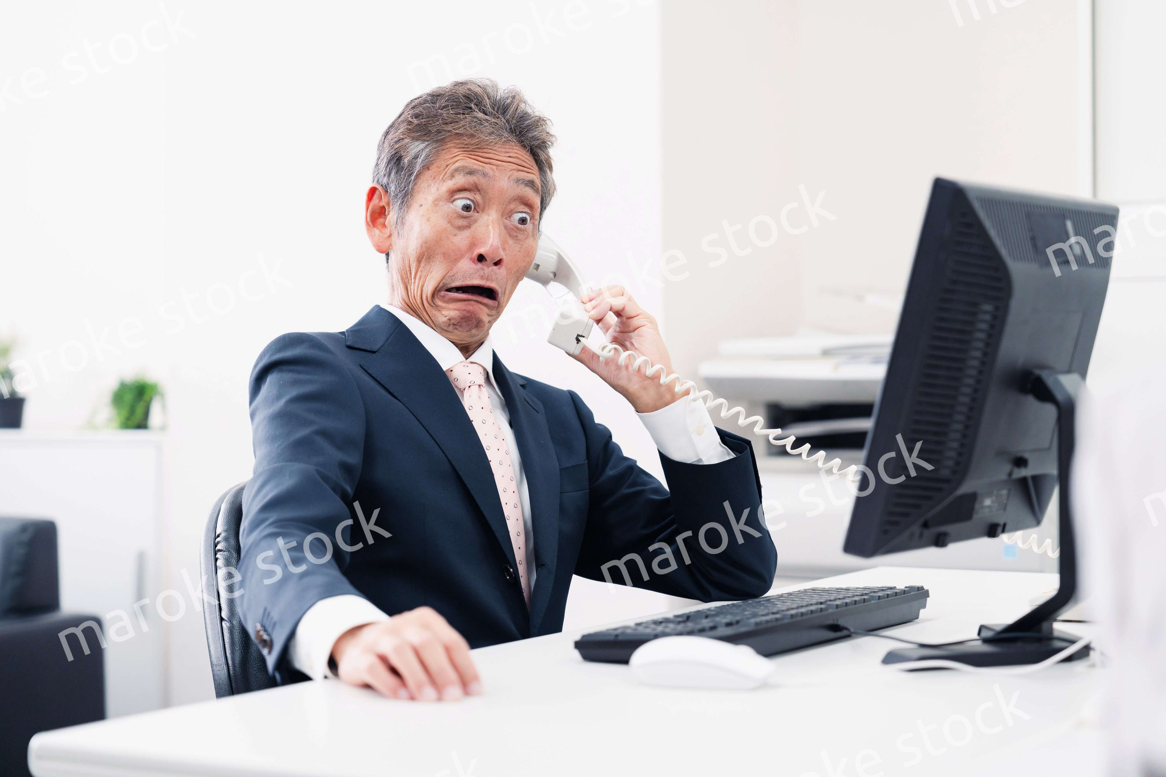電話で驚く管理職の男性