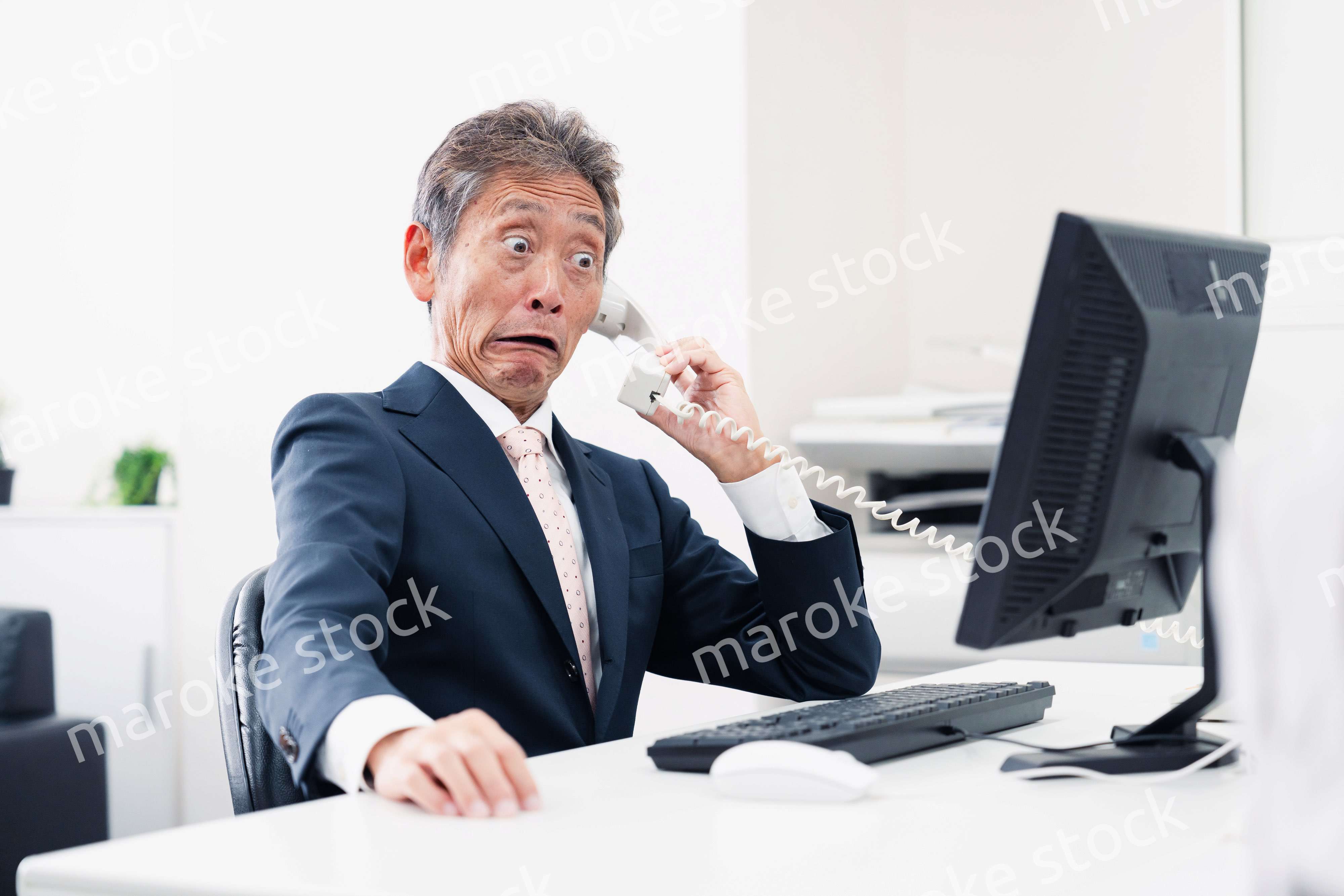 電話で驚く管理職の男性