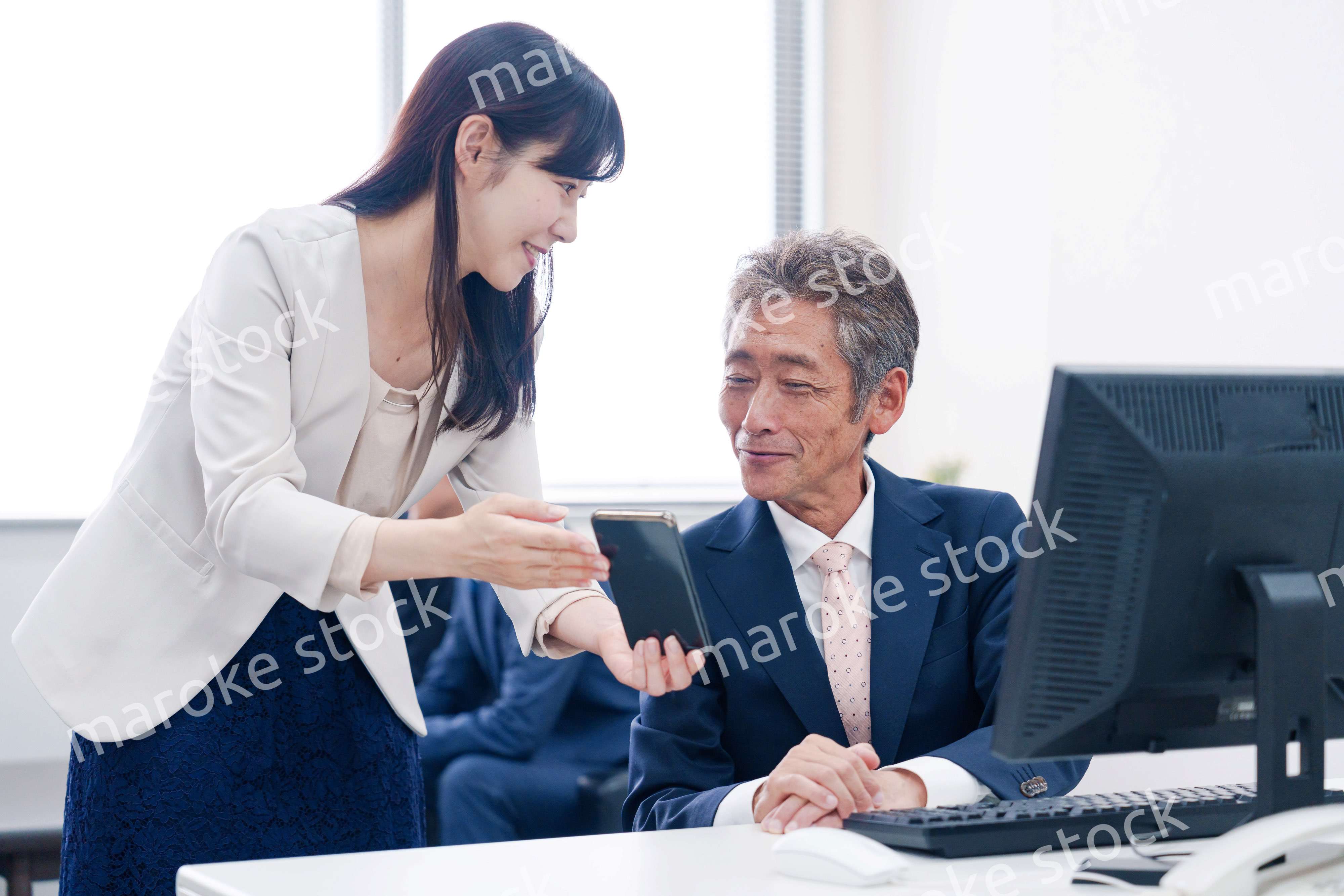 上司にスマホを見せる女性社員