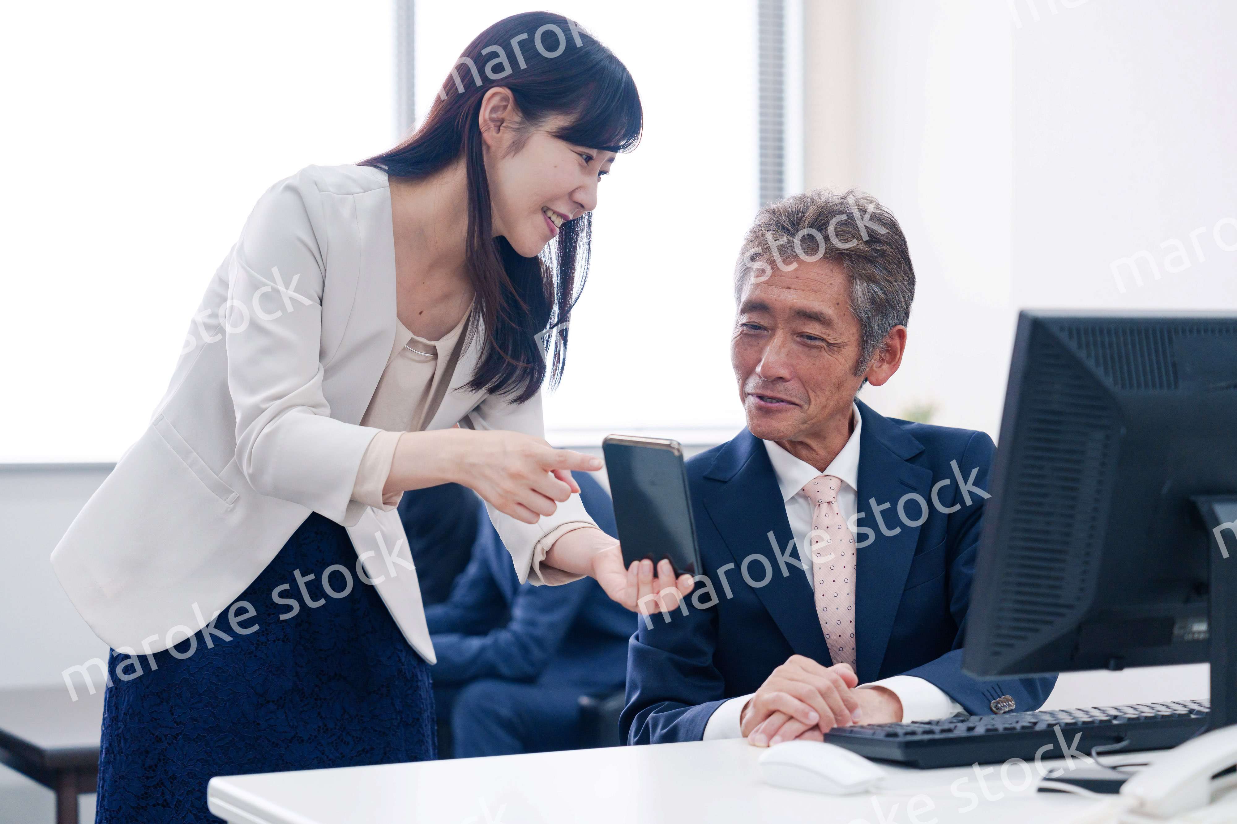 上司にスマホを見せる女性社員