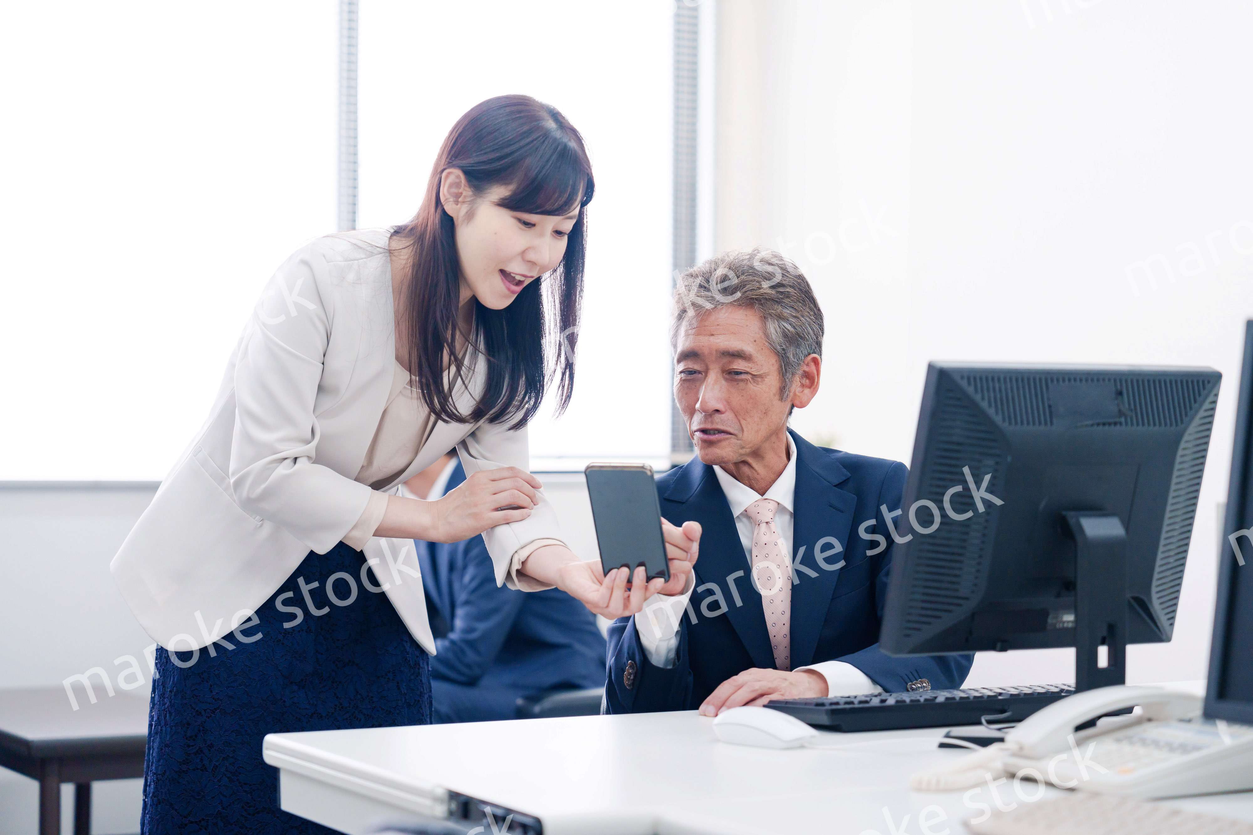 上司にスマホを見せる女性社員