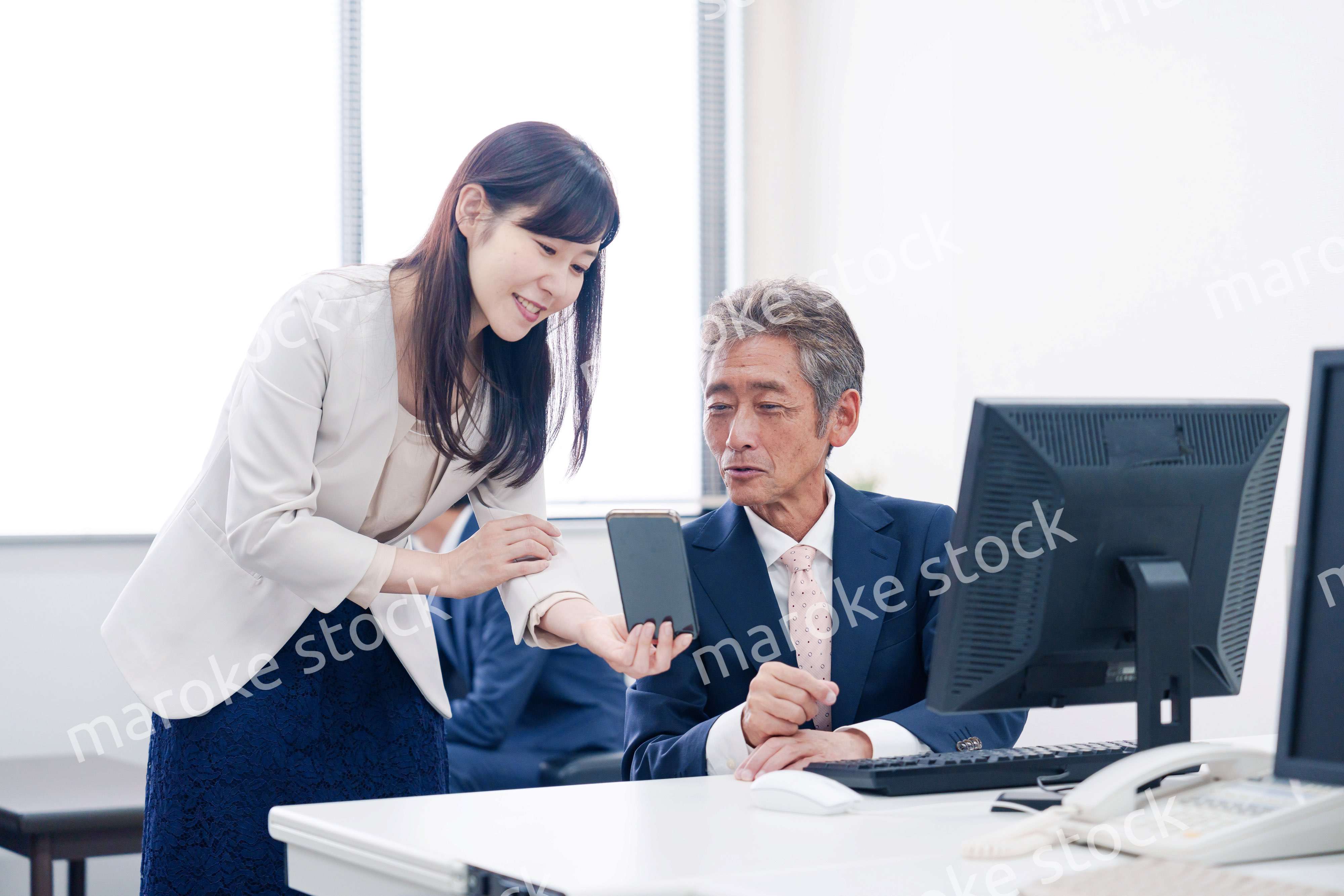 上司にスマホを見せる女性社員